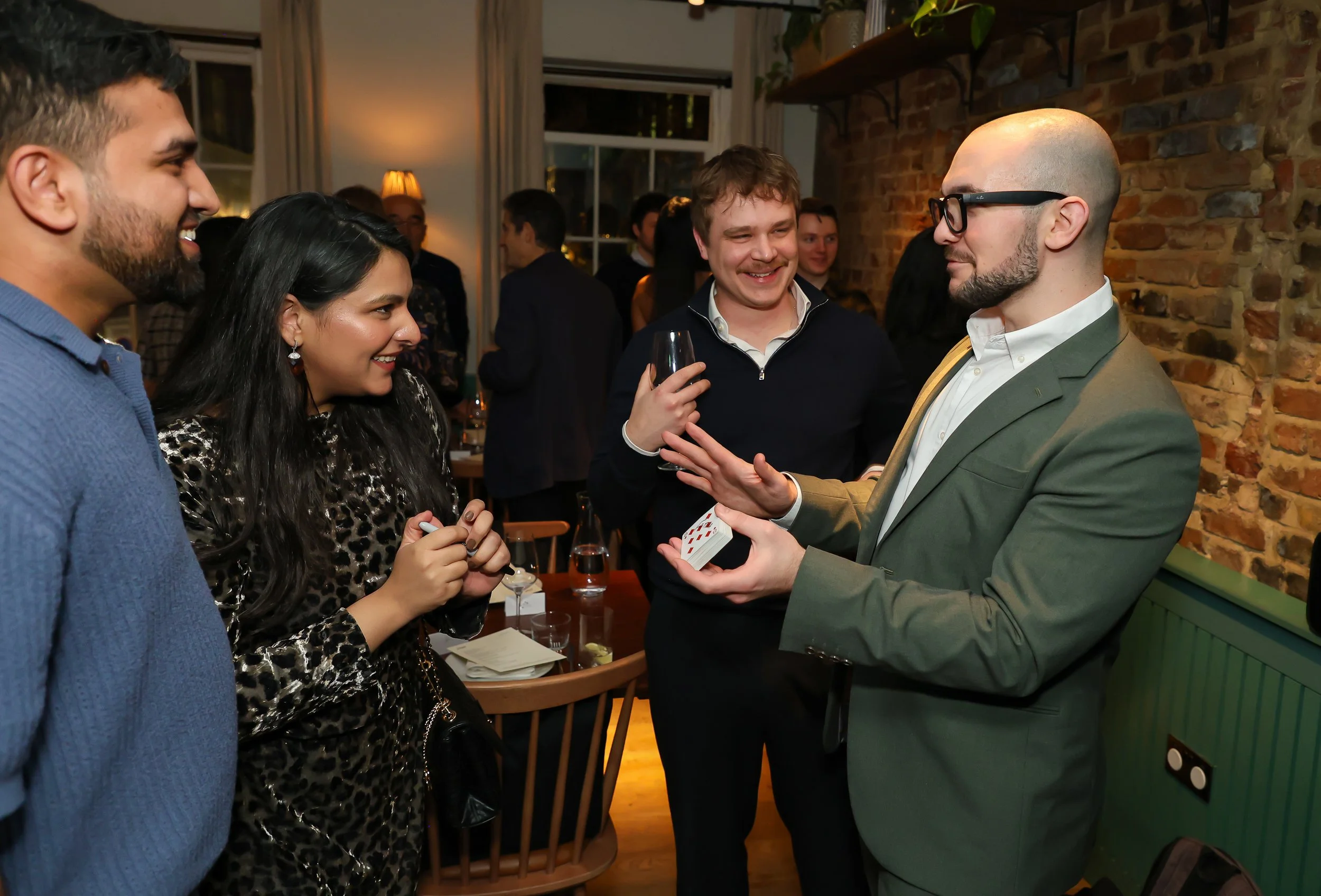 Corporate guests amazed by a live magic trick at a London corporate party.