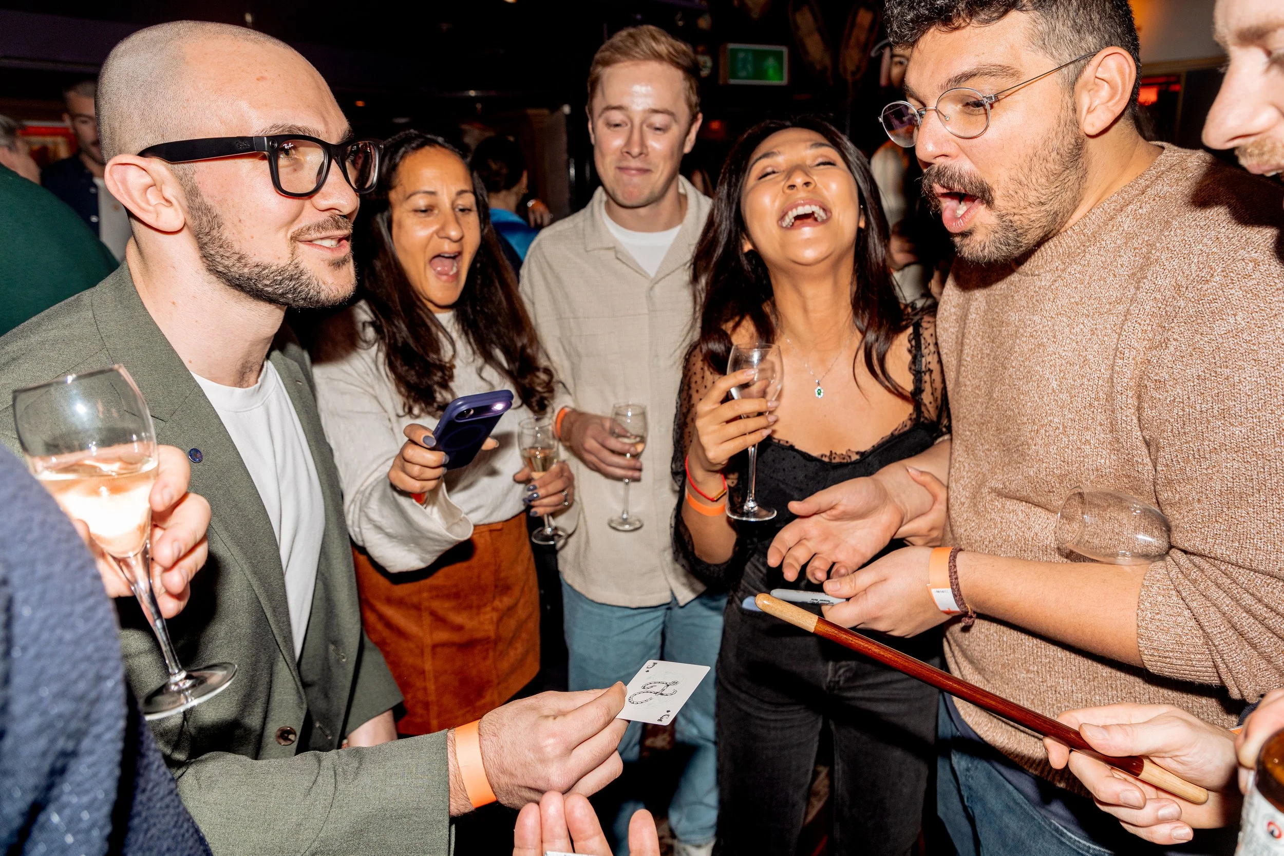 Corporate guests enjoying a thrilling close-up card magic moment.