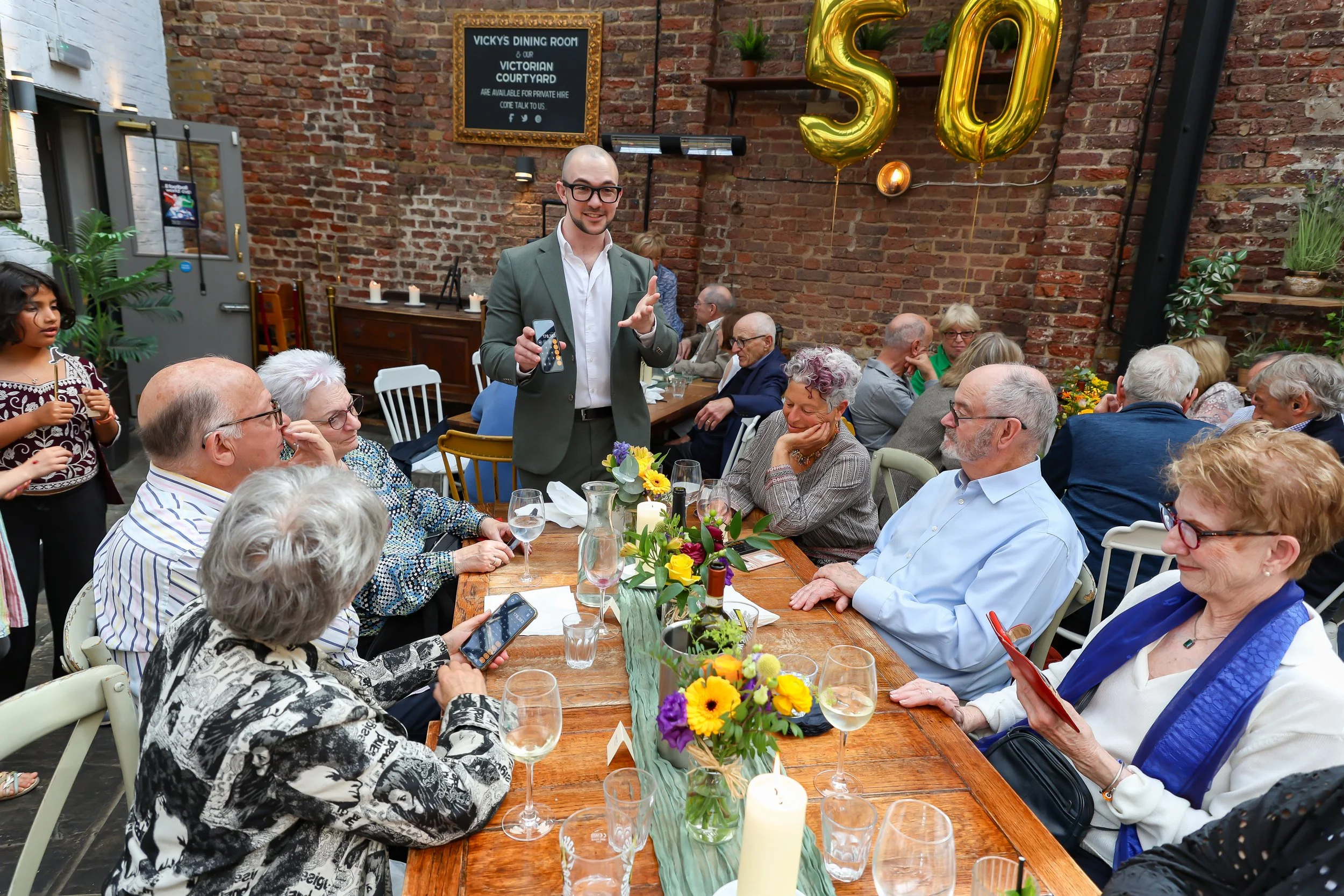 Magician and the guests with his tricks with the guests. 2026-May 3 Rhoda & Baruch Golden Anniversary. 