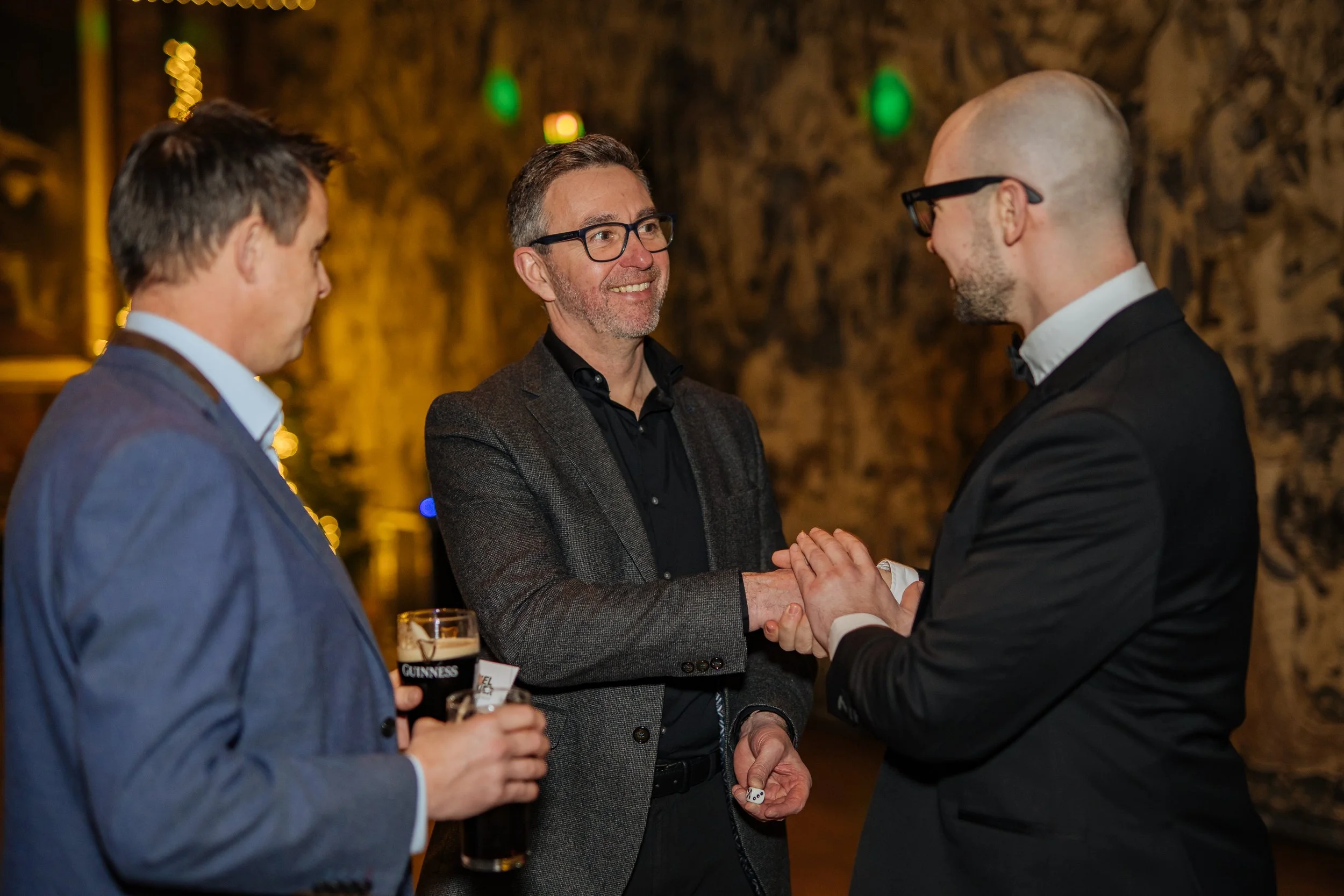 Corporate magician performing close-up magic for corporate executives at event reception.