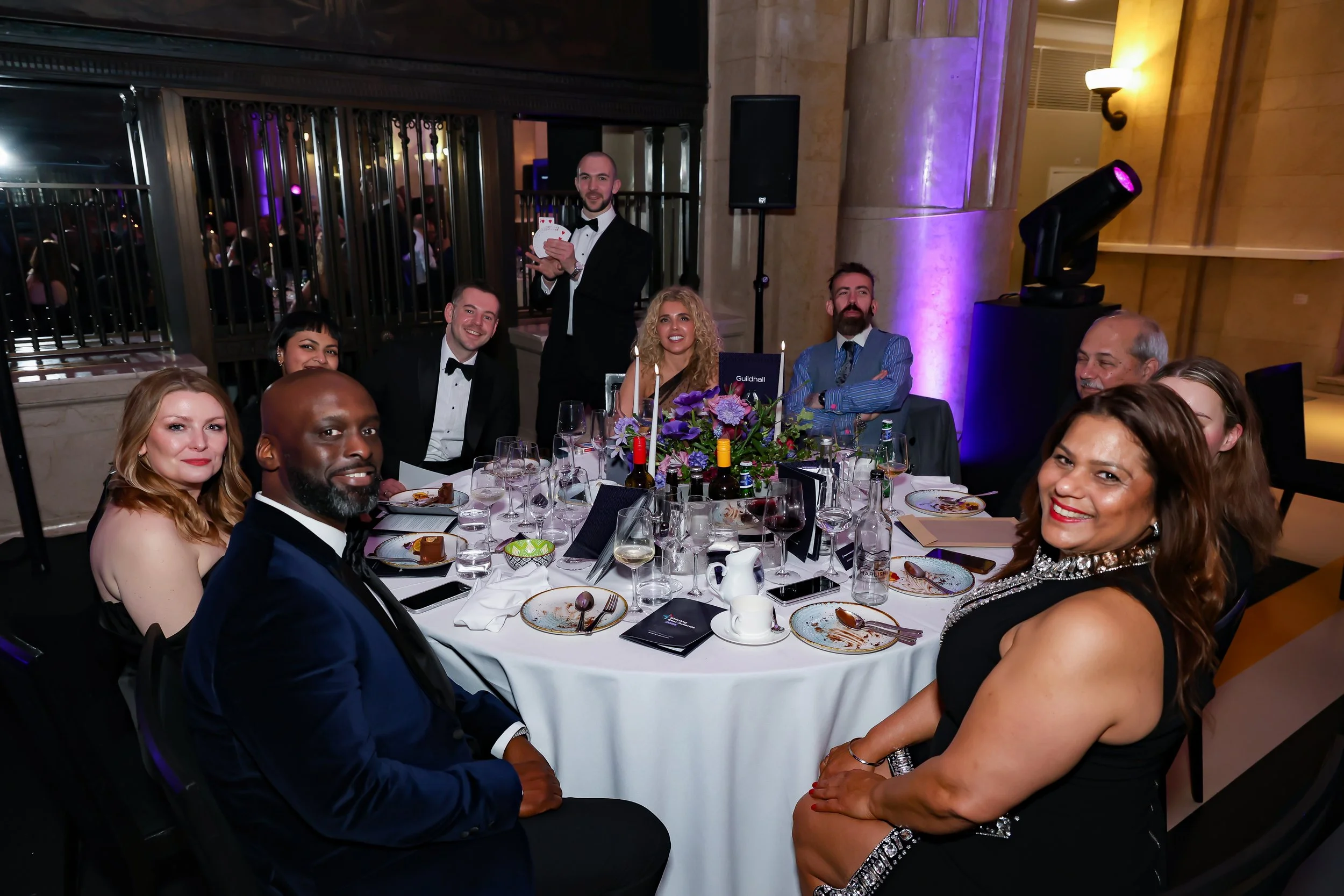 A professional magician delivering table magic during a formal corporate dinner.