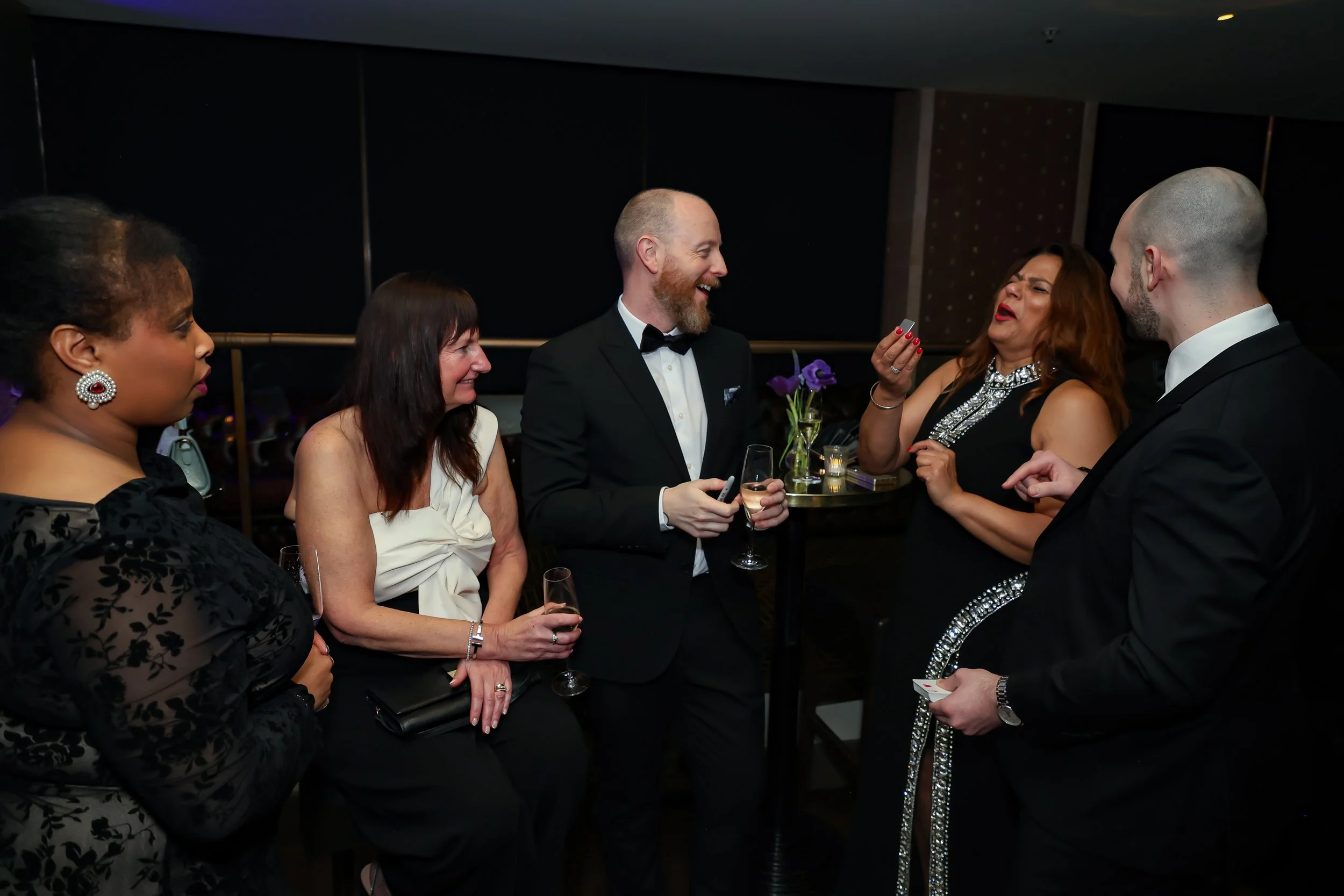 Corporate professionals enjoying with a live card performance by the magician during reception.