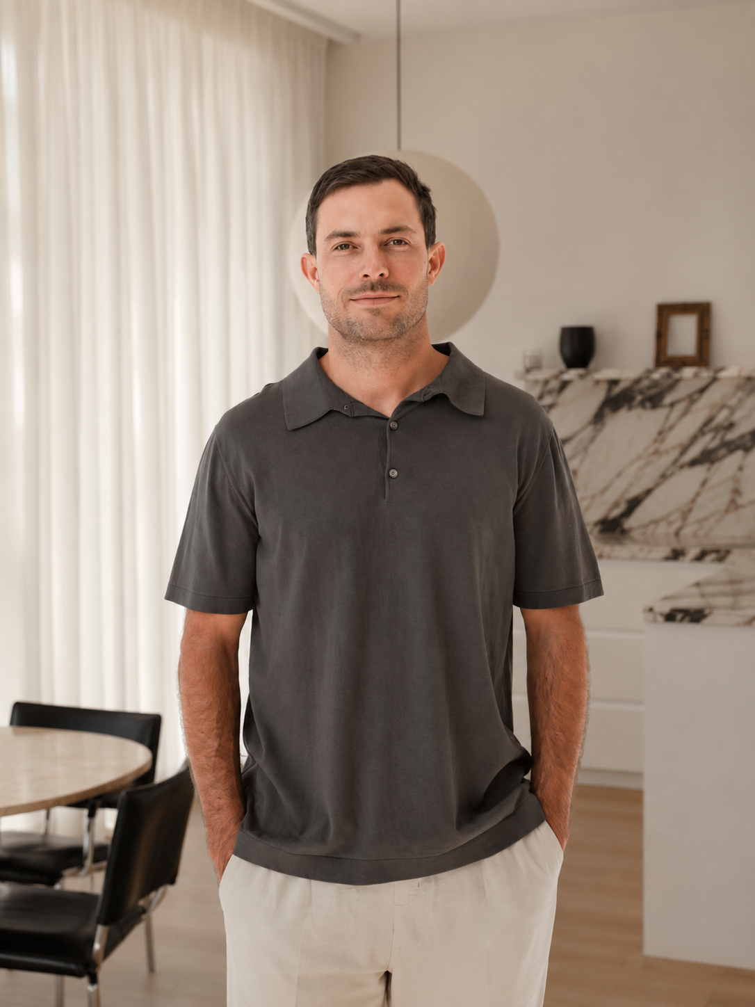Kodi Wulff of Equity Projects and Buywell Group standing in a modern, well-lit living room with light-colored curtains, a marble-topped kitchen counter, and black dining chairs.