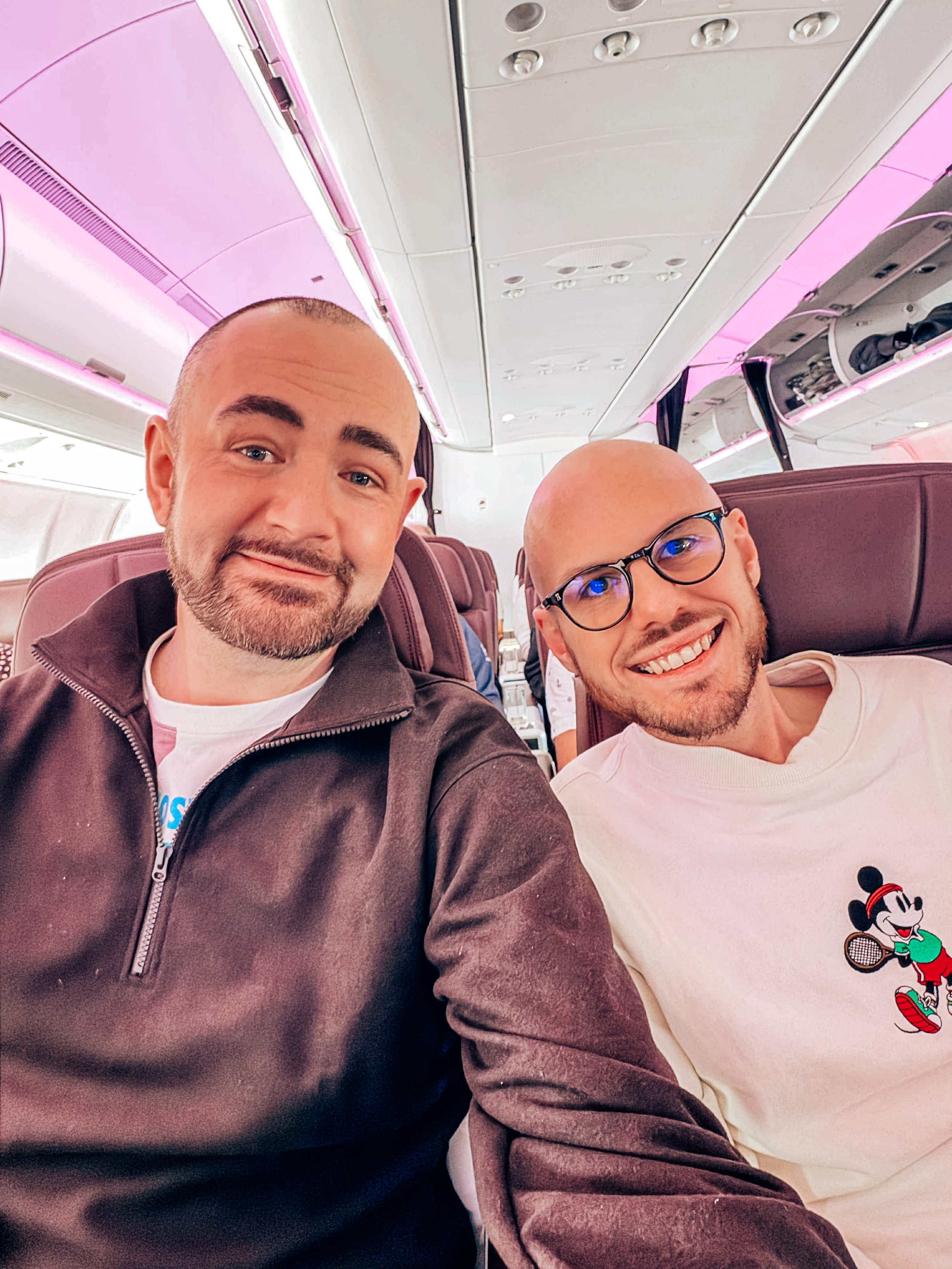 Ben and David sitting in an airplane, smiling for a selfie.