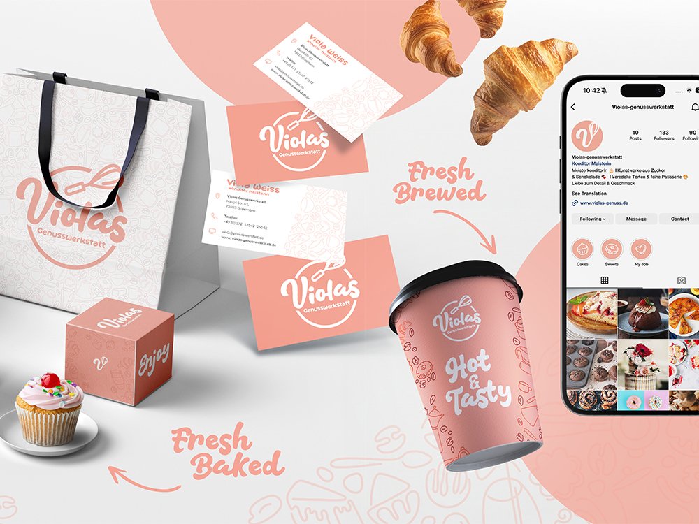 Markenpräsentation von "Violas Genusswerkstatt" mit einem Papiertragetasche, einer Tasse, Visitenkarten, einem Smartphone mit Instagram-Seite und verschiedenen Backwaren, einschließlich Croissants und einem Cupcake.