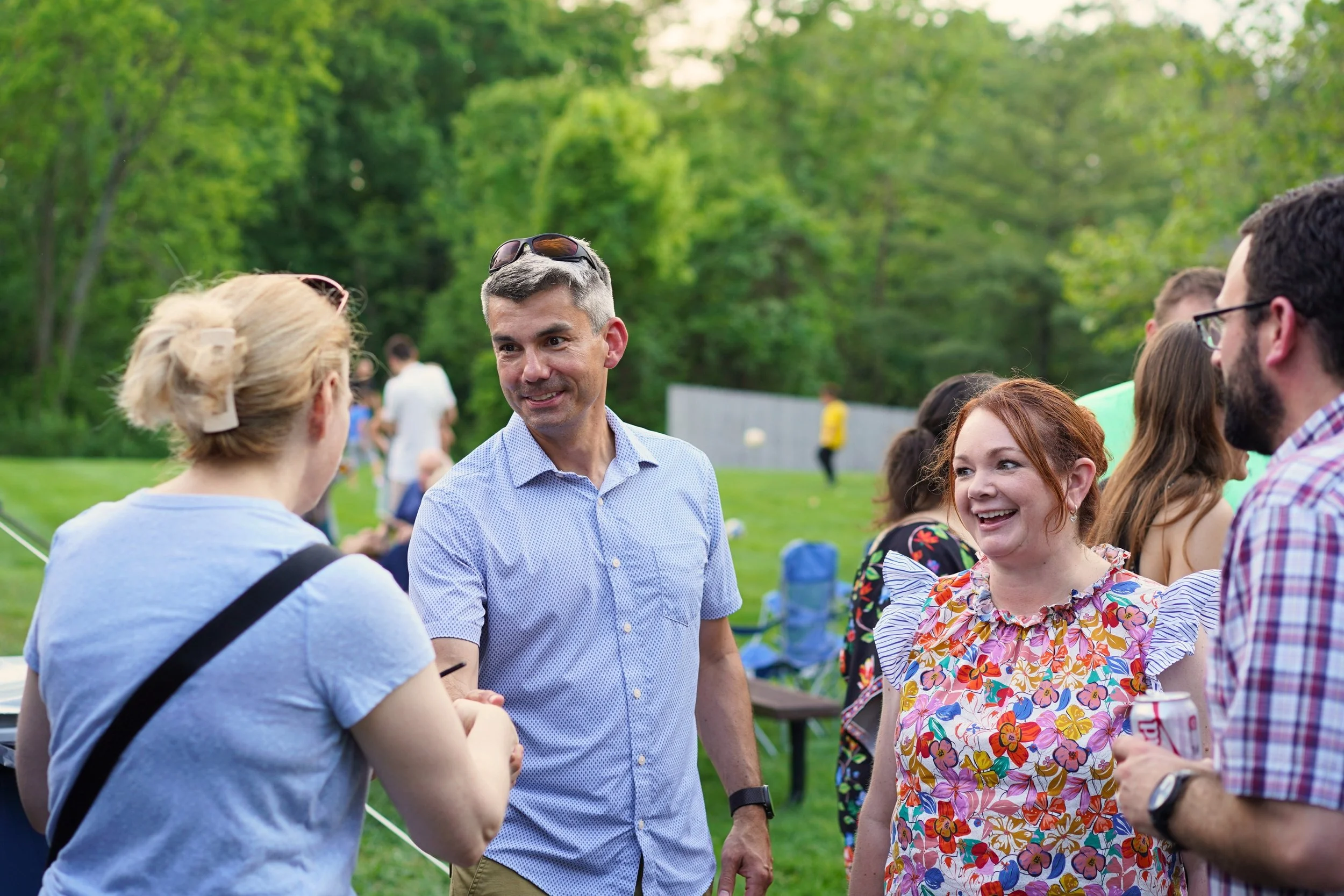 Man smiling outside, shaking hands with a woman