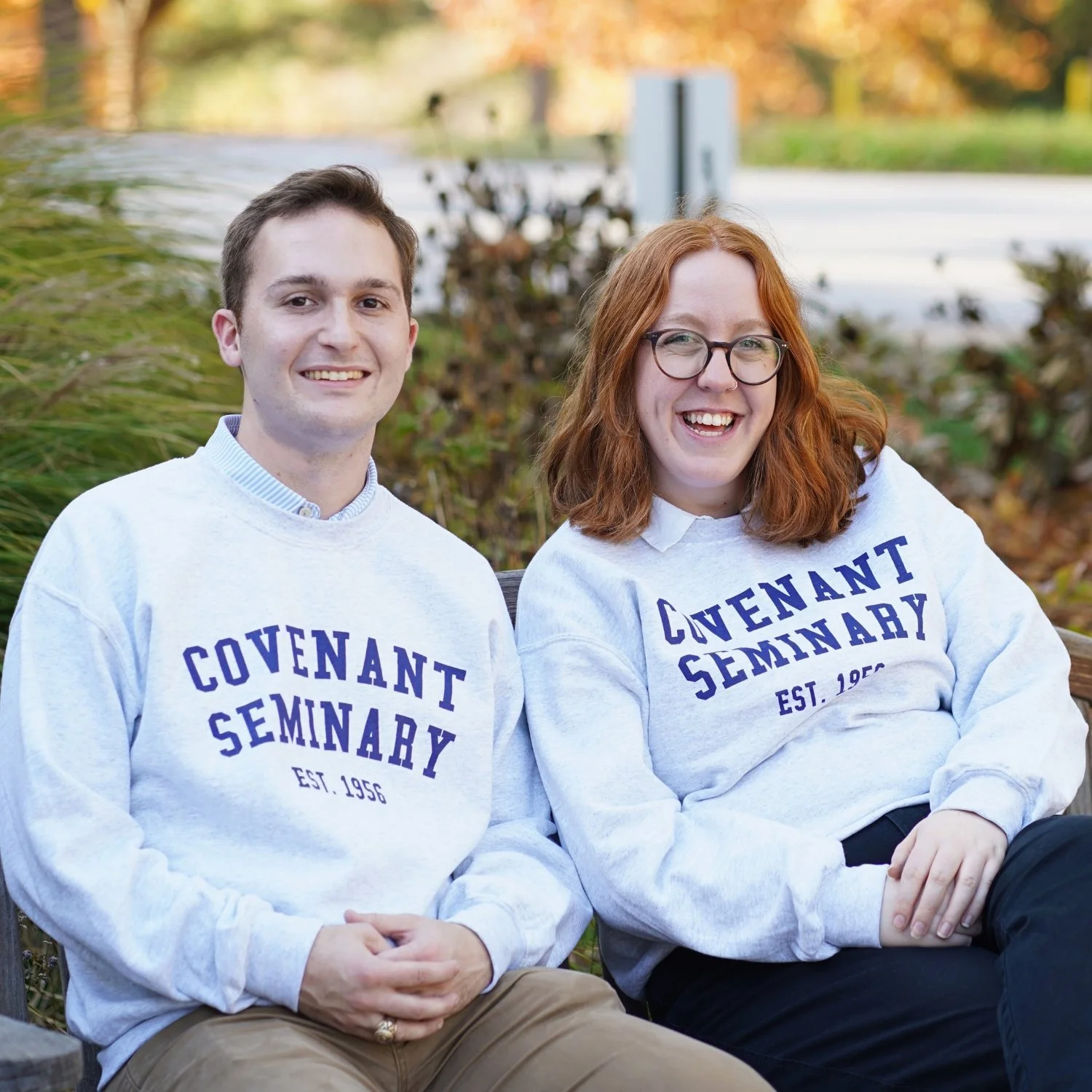 Two students sitting outside, smiling and wearing Covenant Seminary sweatshirts