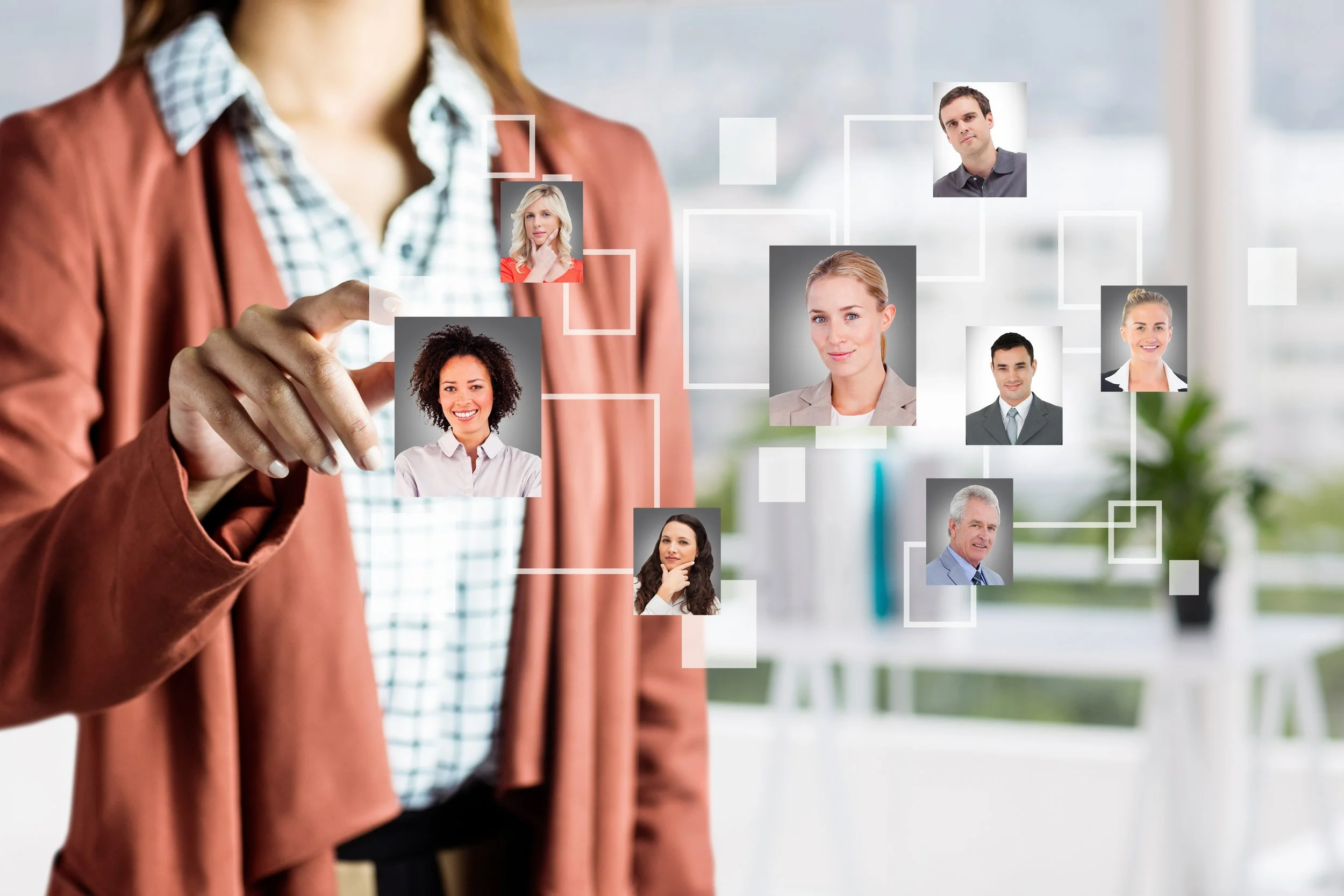 A woman in business attire selecting a profile picture from a digital organizational chart with various smiling faces of diverse professional individuals.