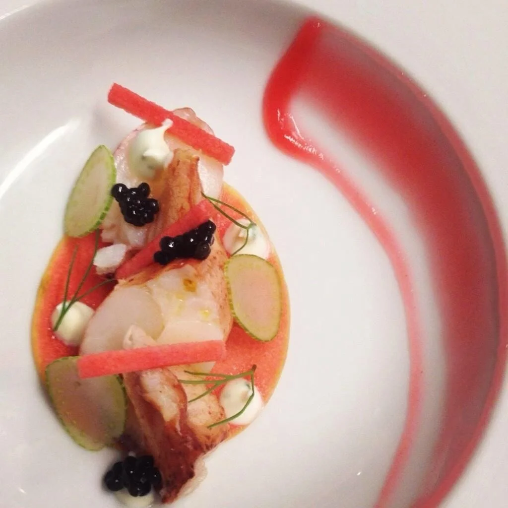 An individually plated lobster course with colorful garnishes.