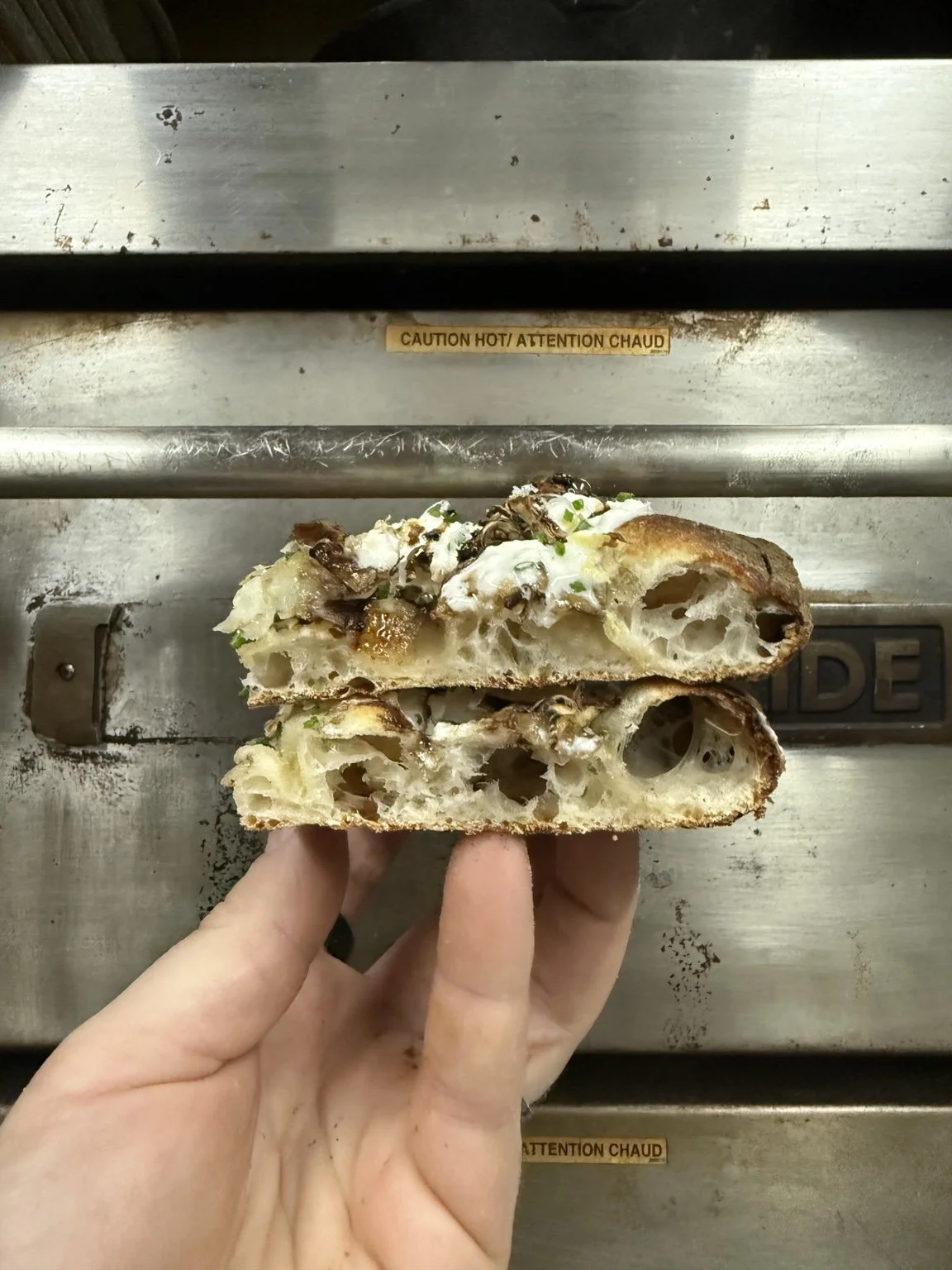 Two stacked pizza slices showing their airy crust and toppings.
