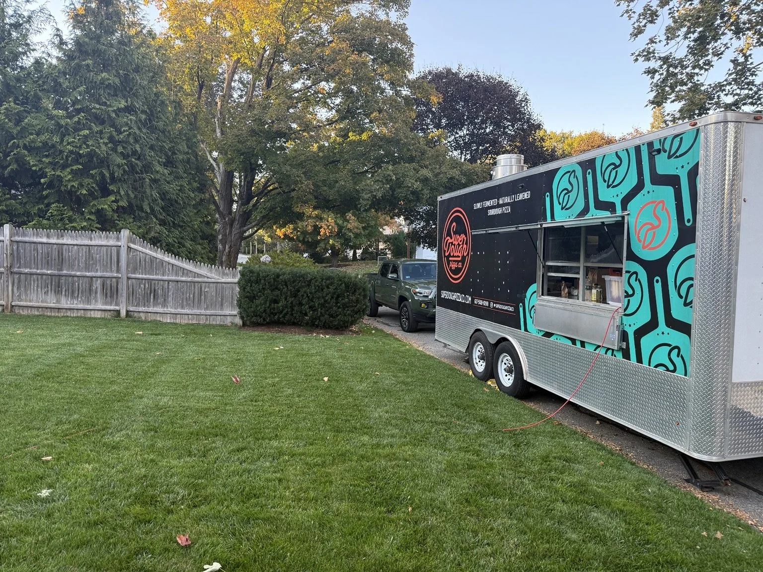 The Super Dough catering trailer set up beside a backyard.