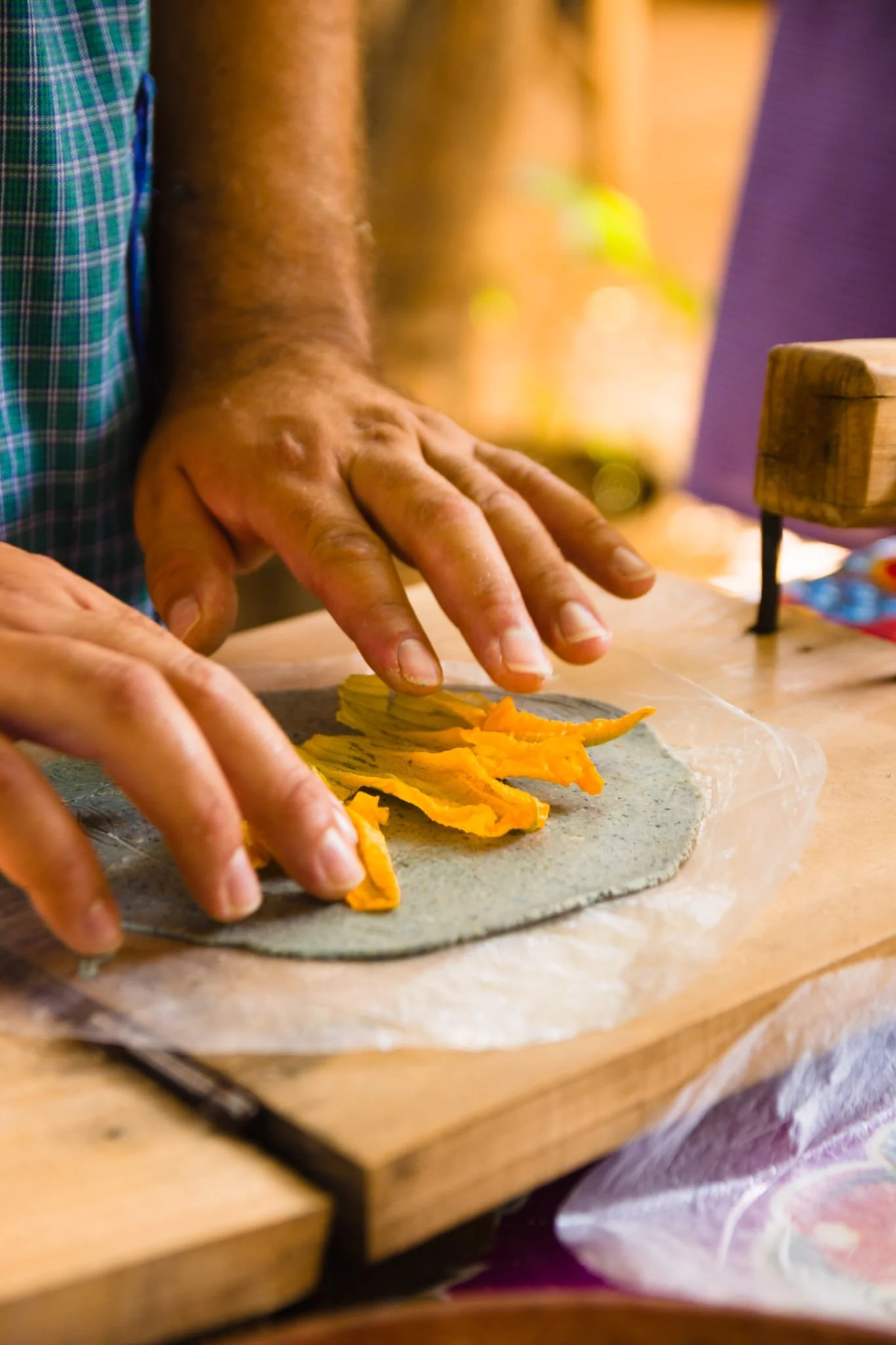 Crafting heirloom blue corn handmade tortillas. Decorated with squash blossoms 