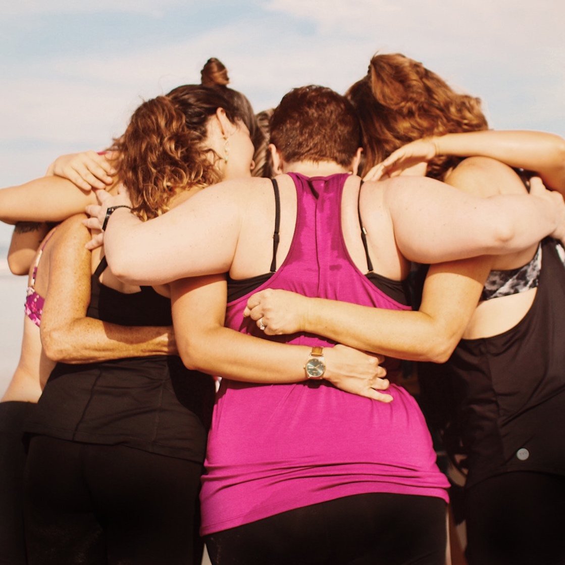 A group of women huddling together in a supportive embrace.