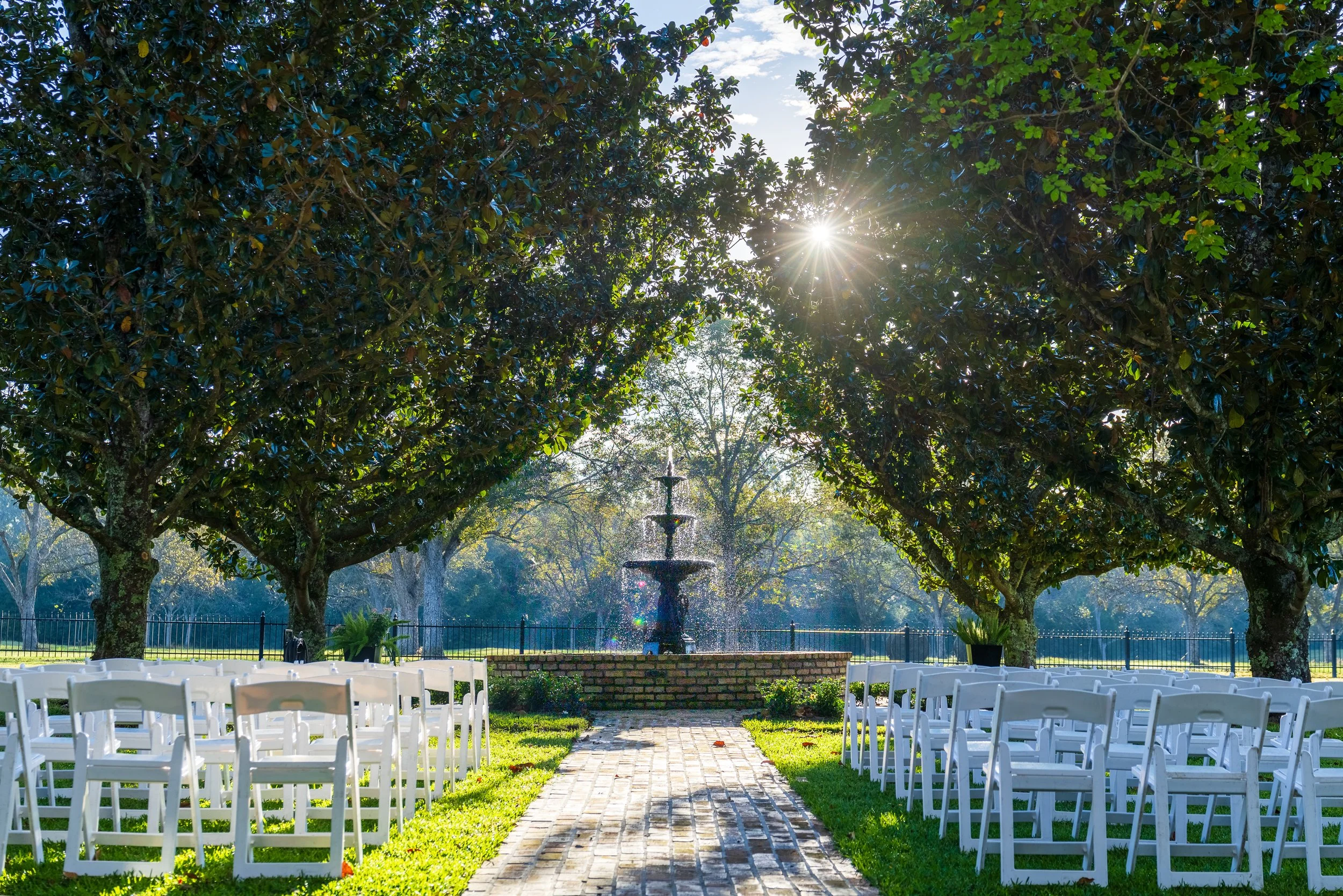 The Magnolia Fountain ceremony location setup with white garden chairs.
