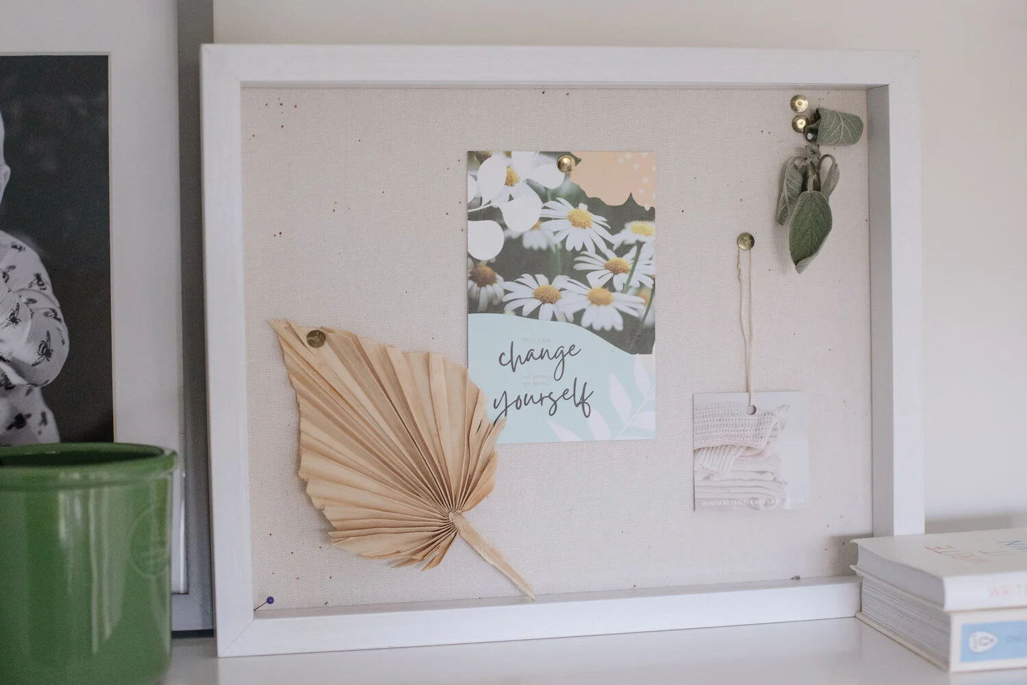Close up of a pin board with a dried floral, and various paper items attached to it.