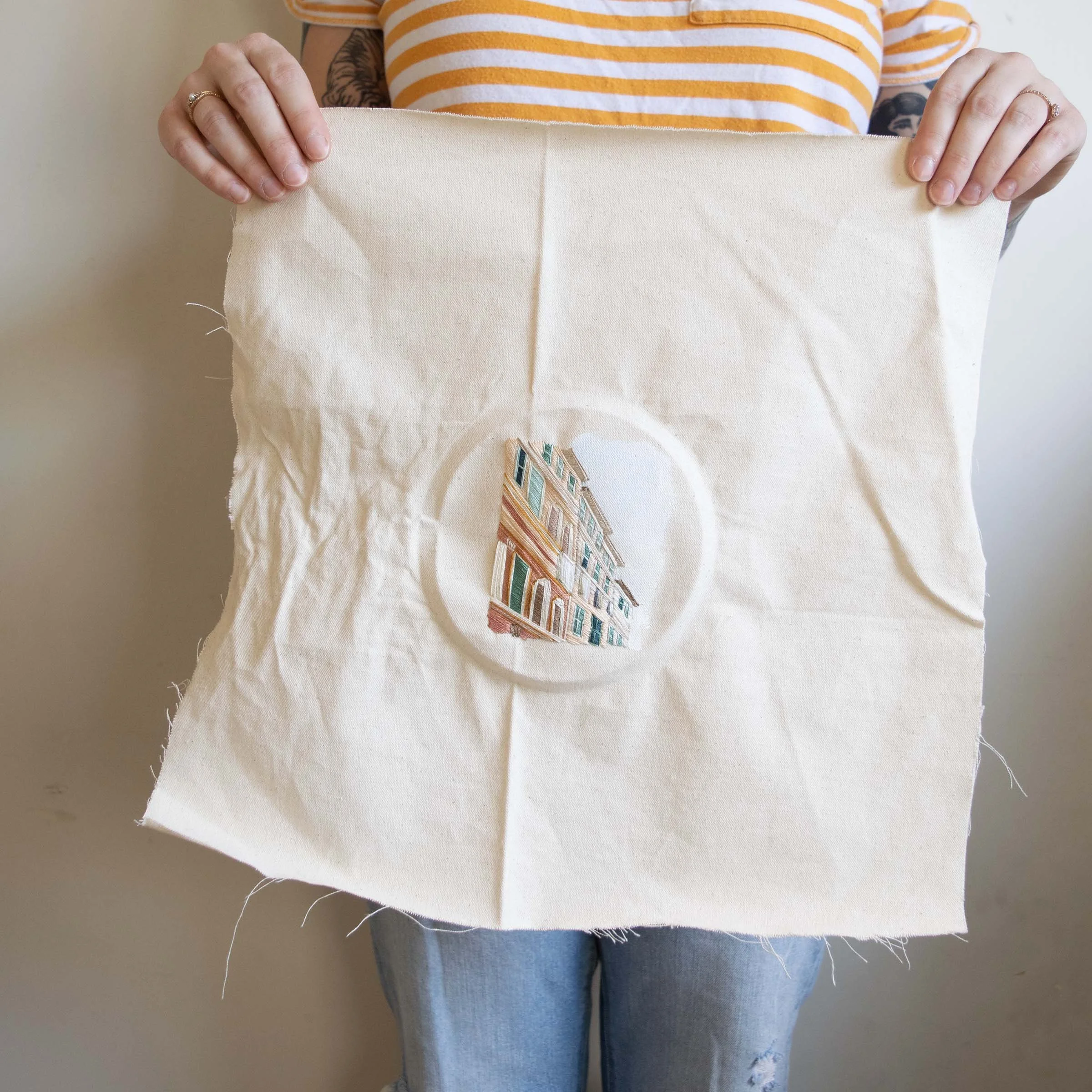 Artist holding original painted and threaded embroidery.