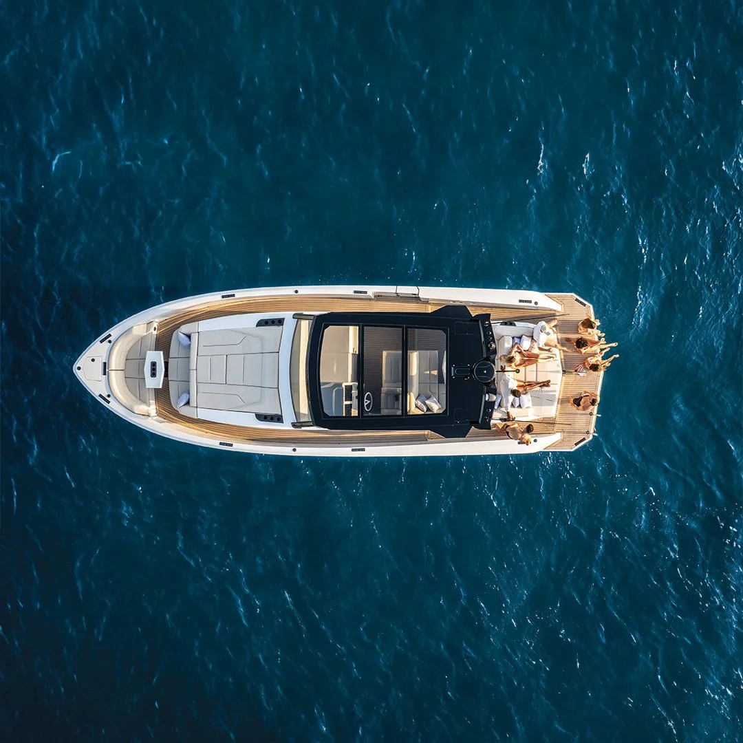 Overhead view of a luxury yacht with people relaxing on the deck, floating on the ocean.