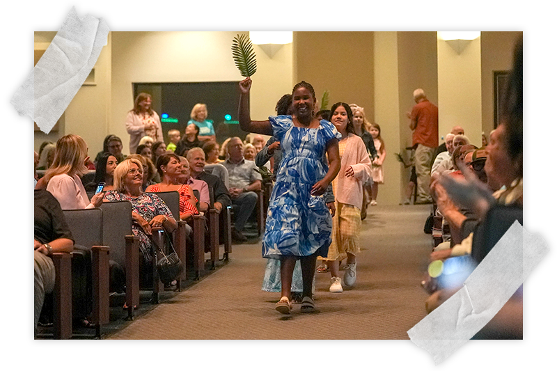 A group of children waves palm fronds as they walk down the aisle at Spanish River Church