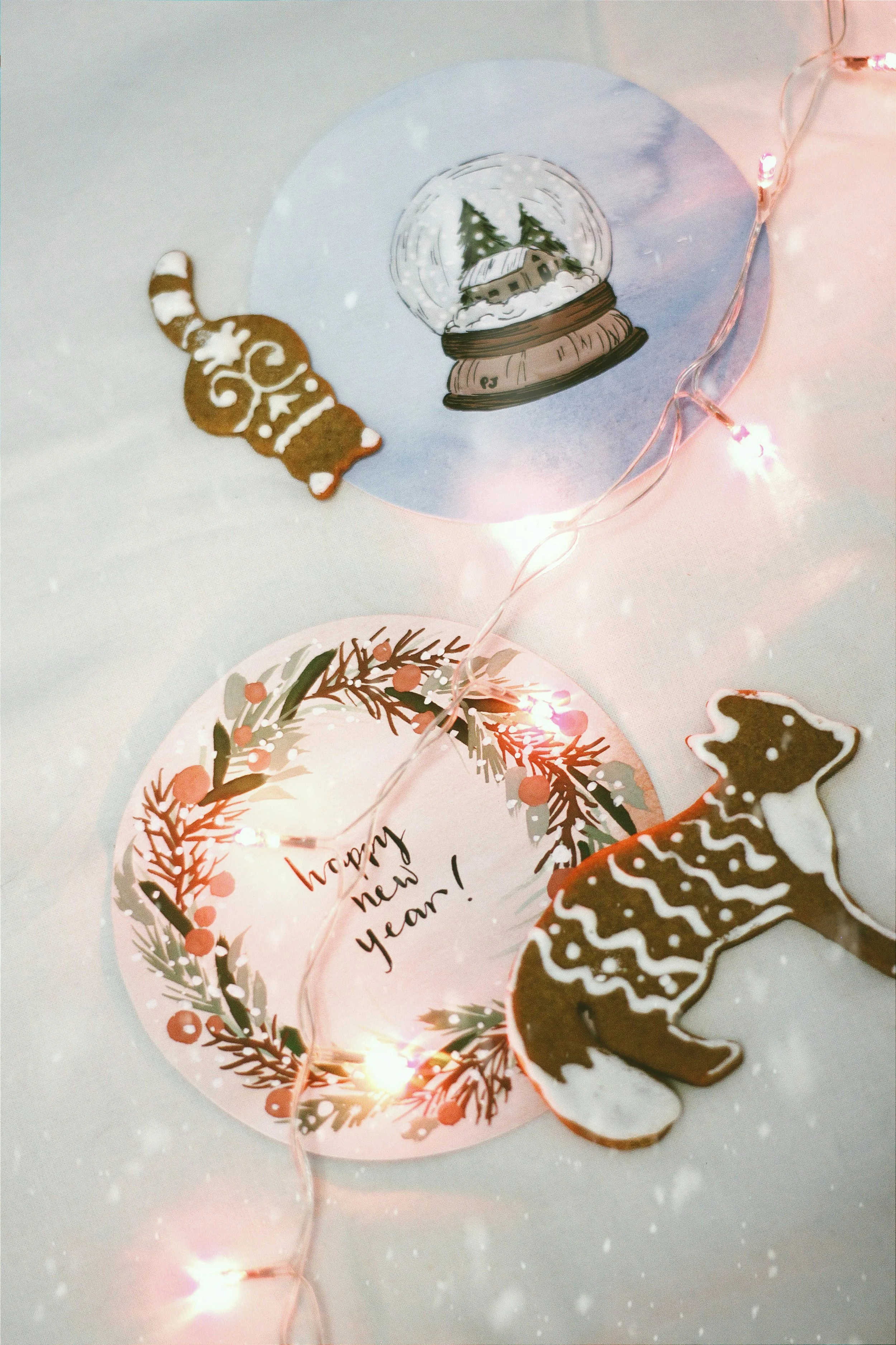 Christmas-themed gingerbread cookies, a snow globe illustration, a holiday greeting card with holly, and Christmas string lights.