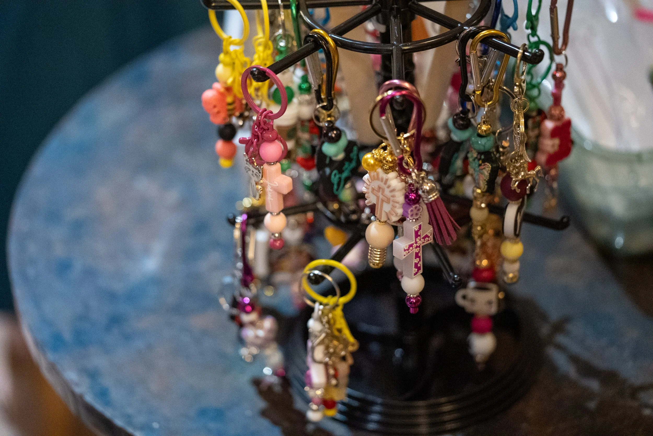 Colorful keychains and charms hanging on a black display rack.