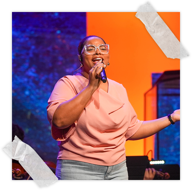 A woman in a peach shirt smiles and sings a song of worship at Spanish River Church