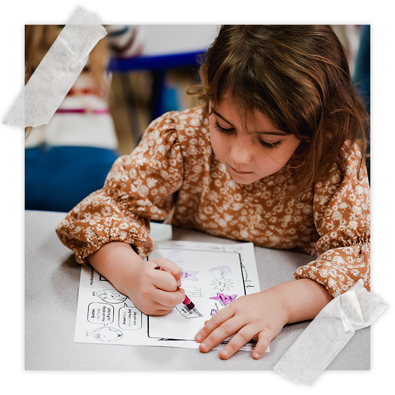A girl uses crayons to color a craft at SRC Kids