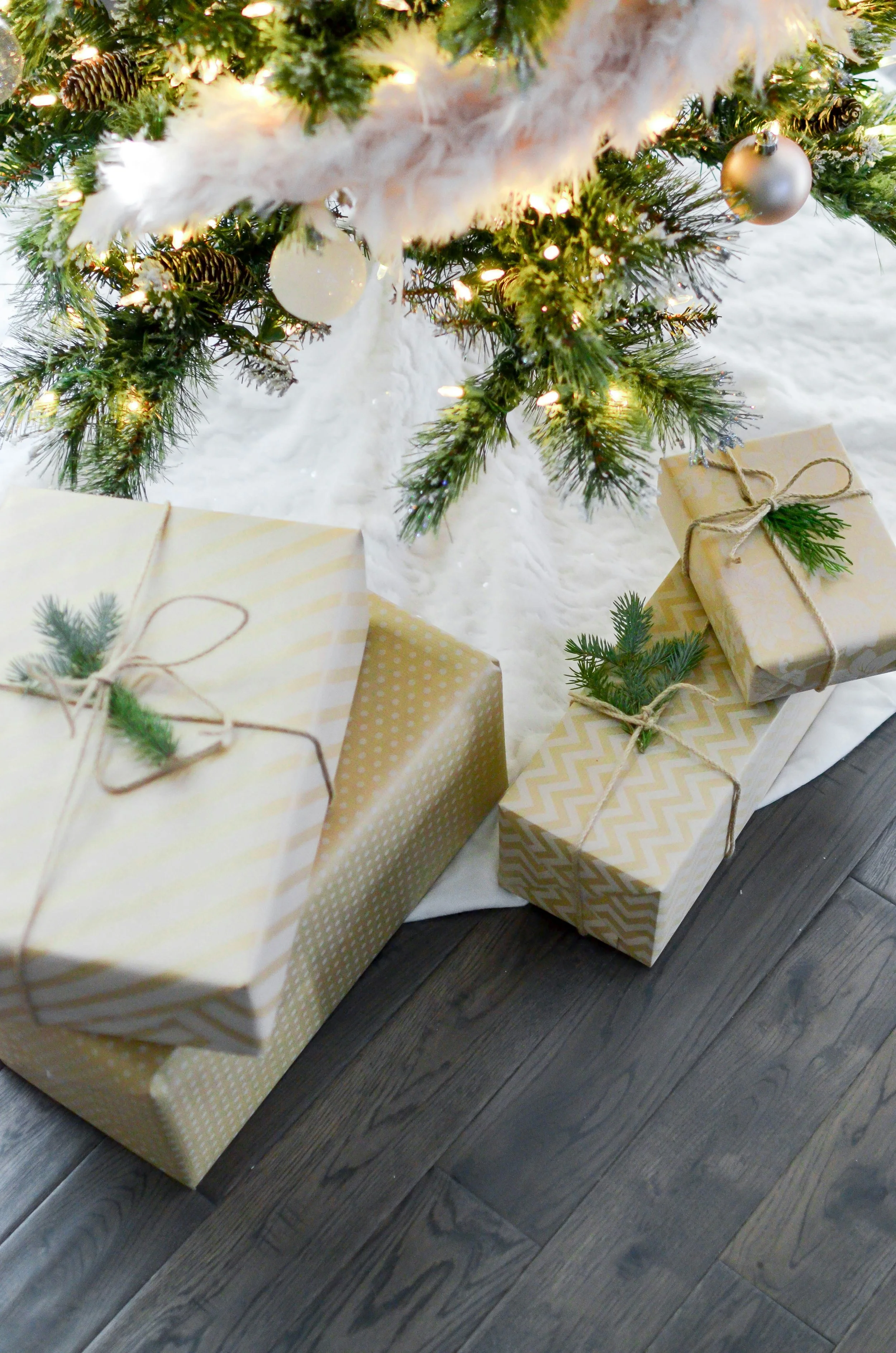 Christmas presents under a decorated Christmas tree on a wooden floor.