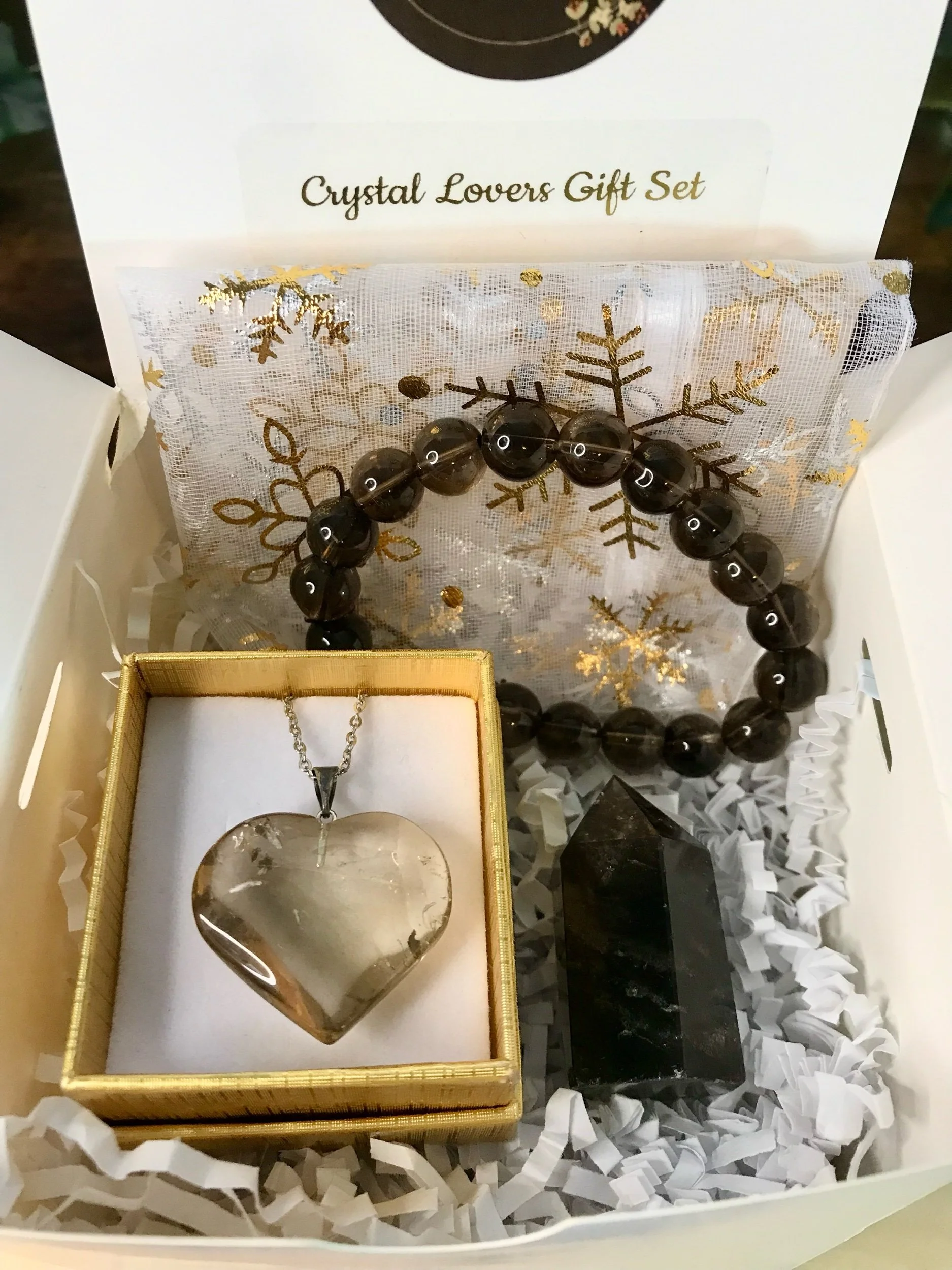 Open gift box containing a black and white marble bracelet, a polished black and white heart-shaped stone, and three black and white polished stones, with red gift paper and branding labels from Luna & Soul.