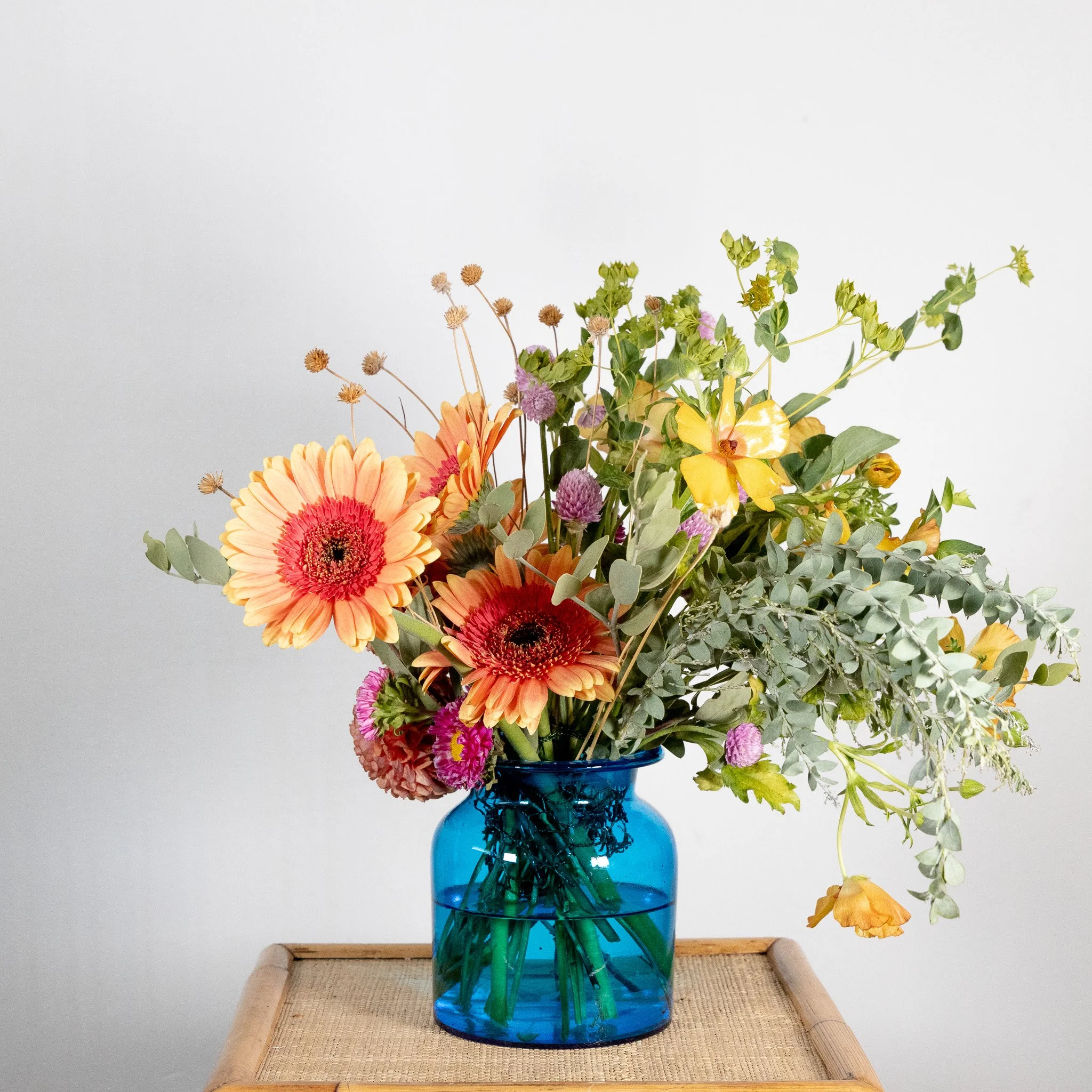 Vase with a colorful bouquet of flowers on a wooden table.