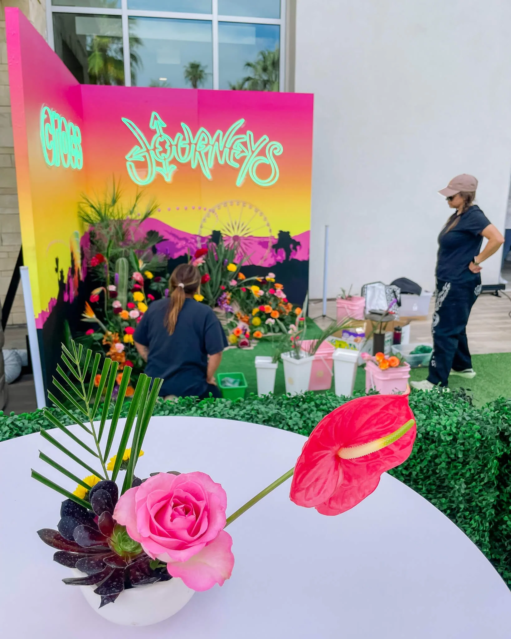 Two floral designers assess the flower installation they are designing on site at a brand activation event.