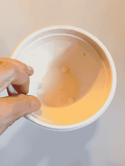 A hand flips one of the compostable cups over to show the material of the cup wasn’t affected by the water.