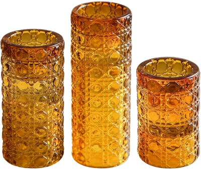 Three amber-colored glasses with textured exteriors, standing side by side.