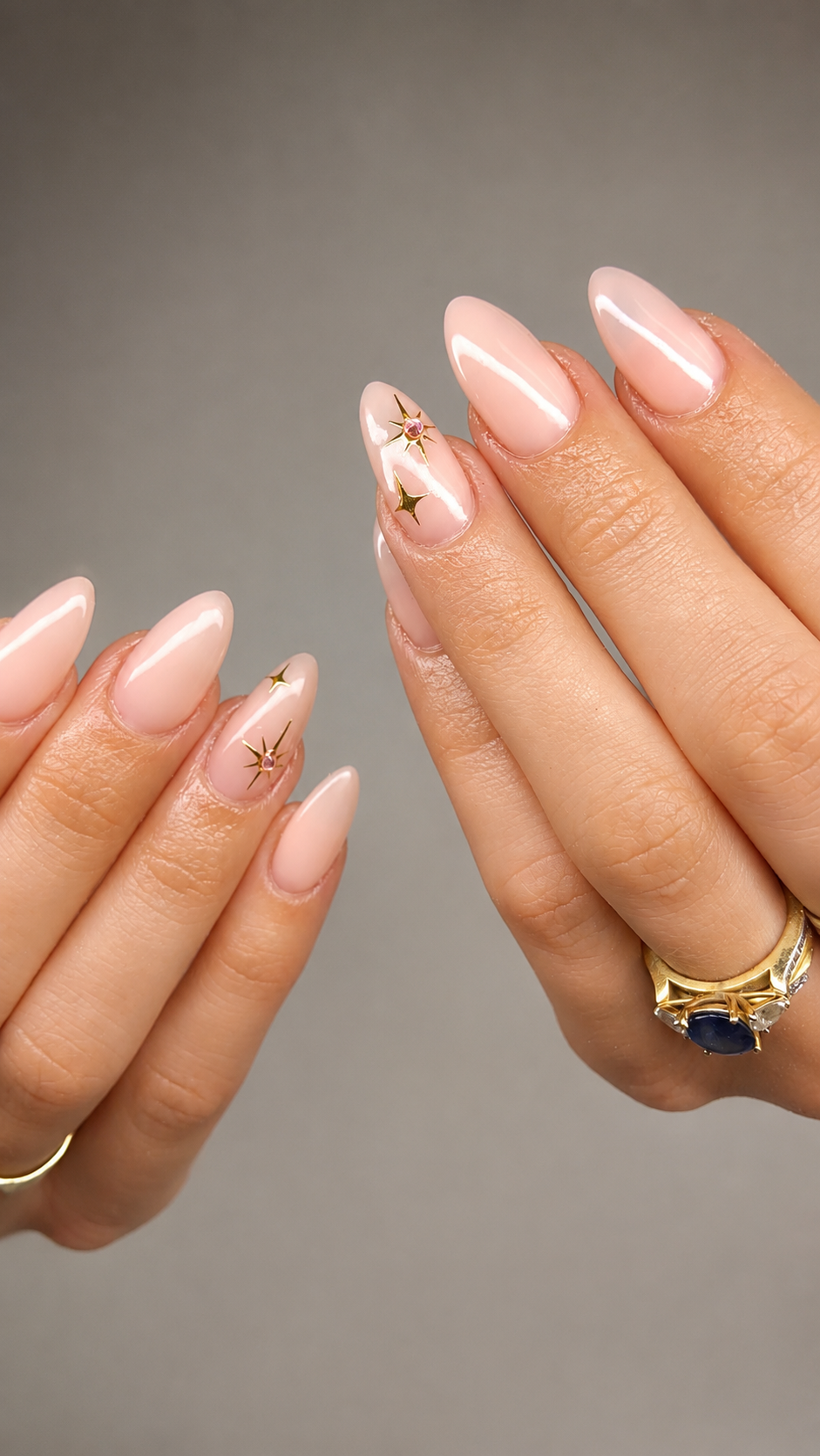 Close-up of a hand with long, metallic, black, pointed nails, wearing a silver ring, against a white satin fabric background.