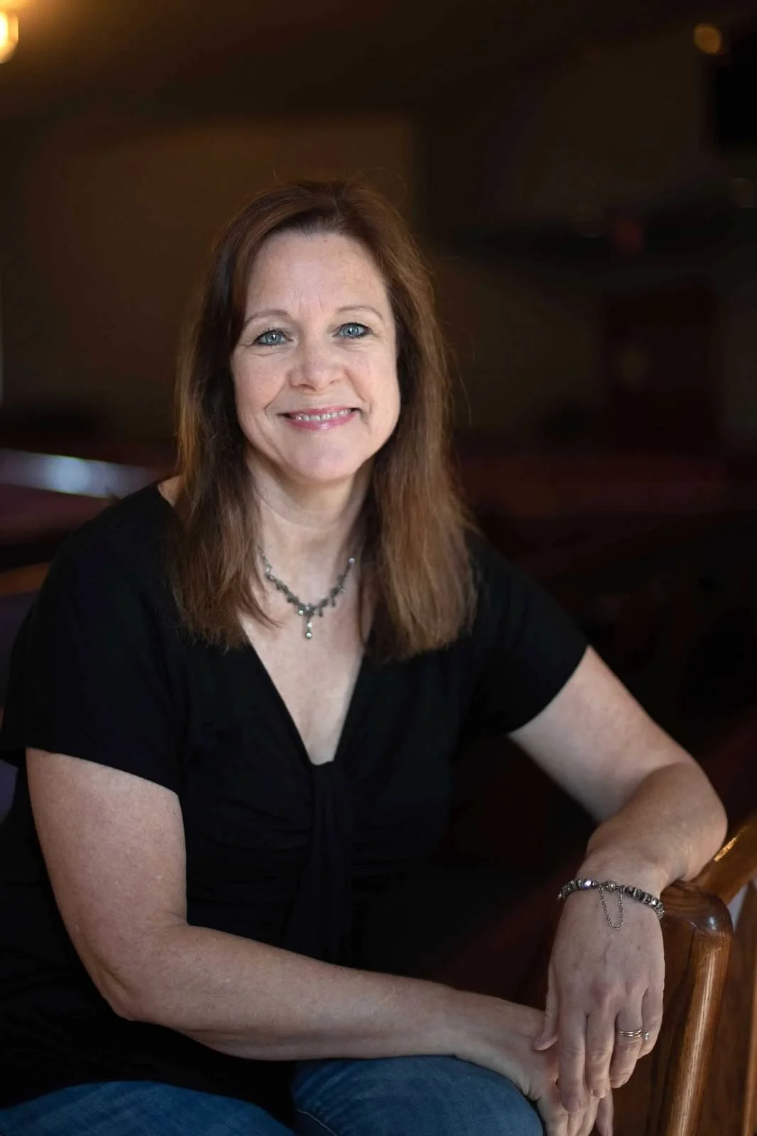 dark haired middle aged  white woman sitting and smiling