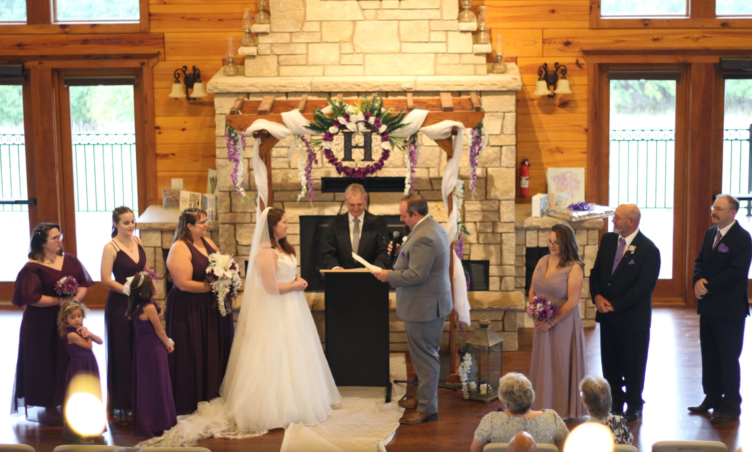 Bride and groom in front of fireplace and arbor sharing vows