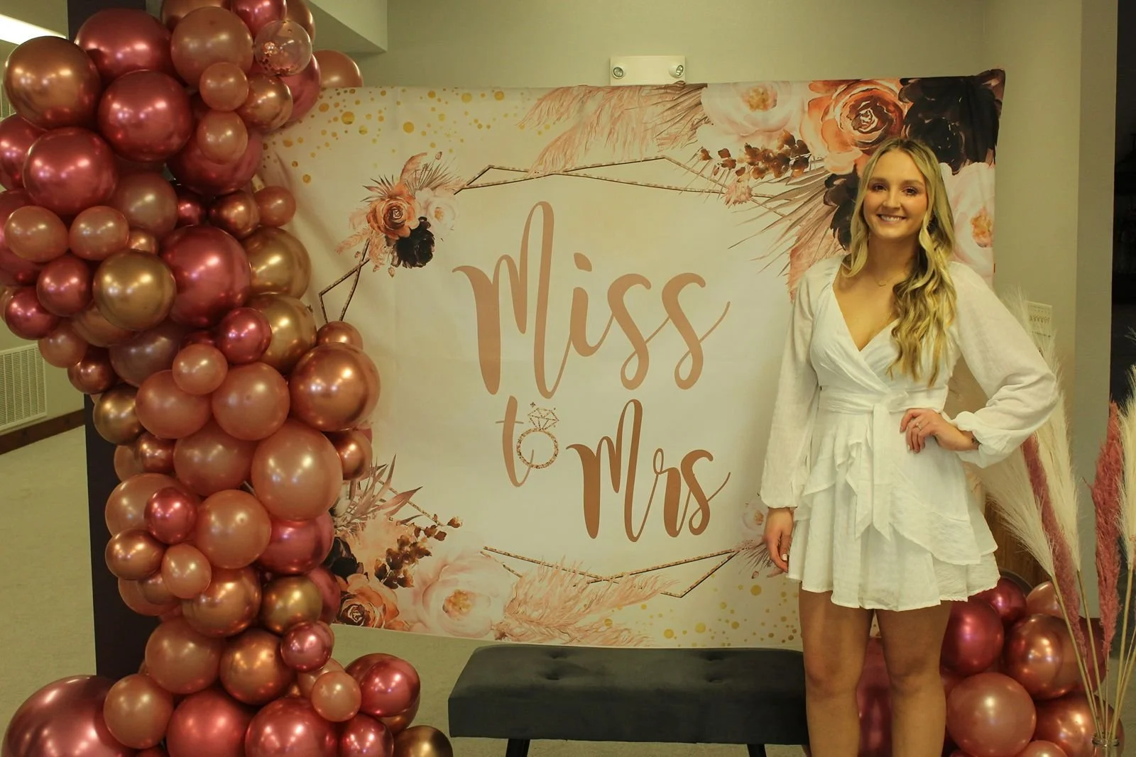 Bride with balloons and sign at wedding shower in Clay Center Kansas venue.