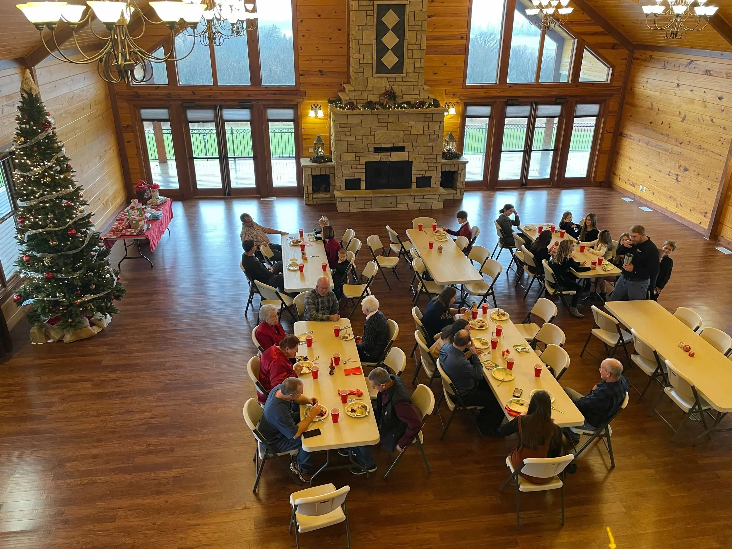 Group Christmas party with large fireplace and decorated tree in tall room at Life's Finer Moments venue.