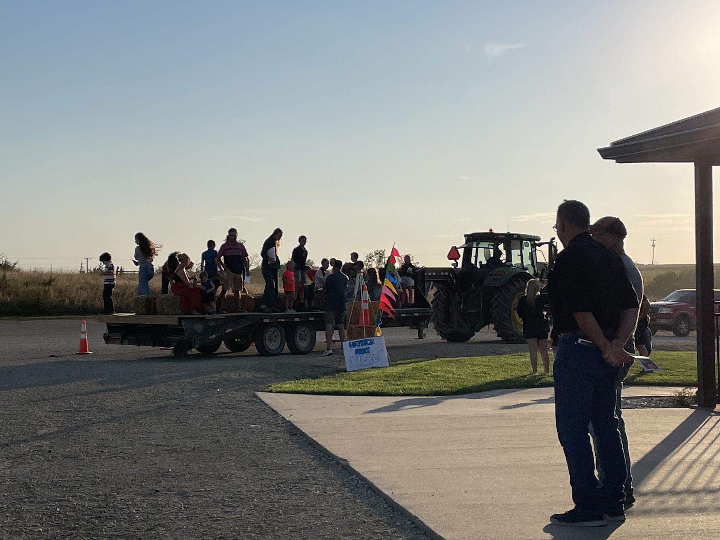People loading on hayrack ride trailer pulled by tractor