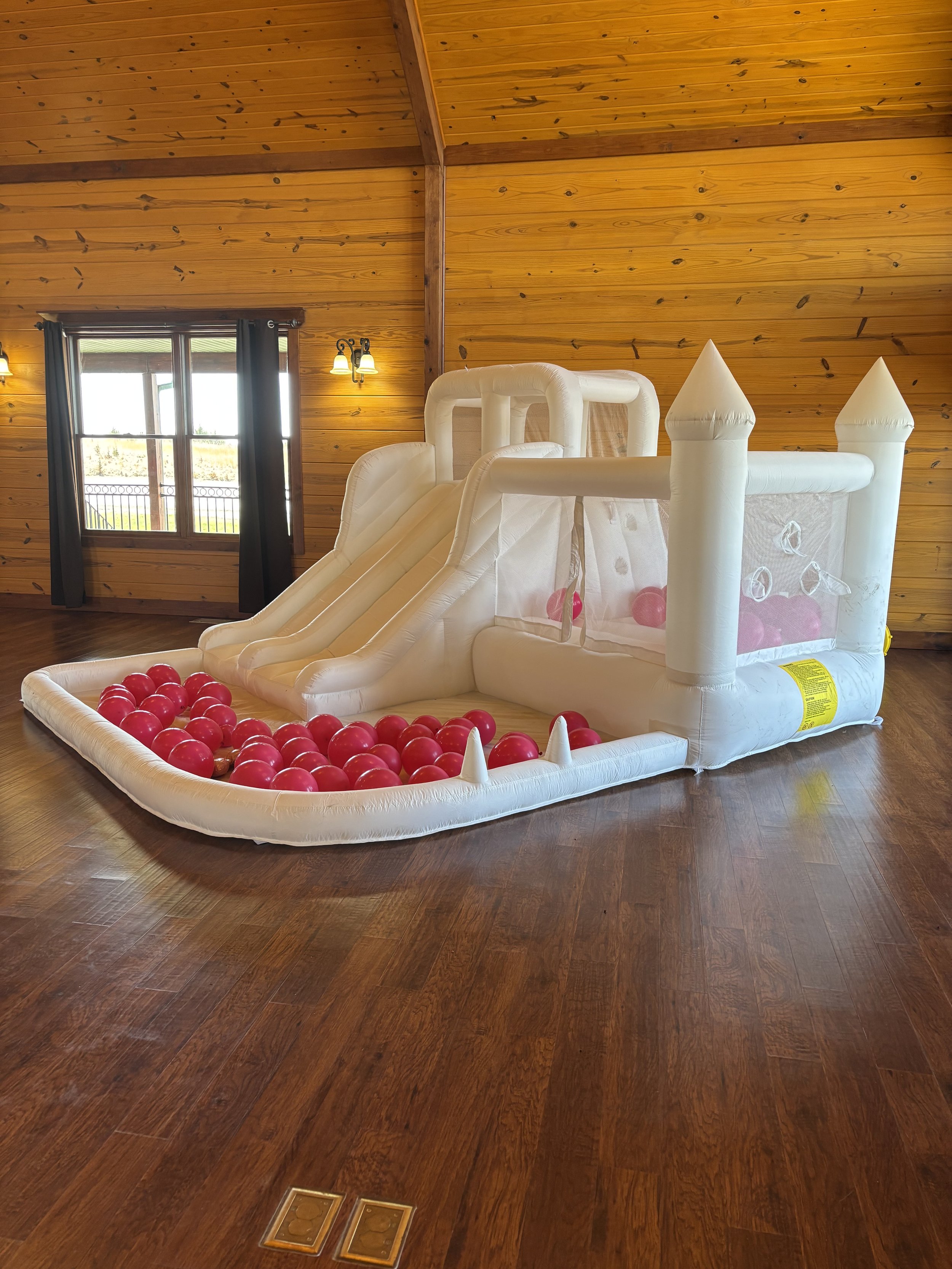 Bounce House castle with a slide into red balloons at birthday party venue Life's Finer Moments.