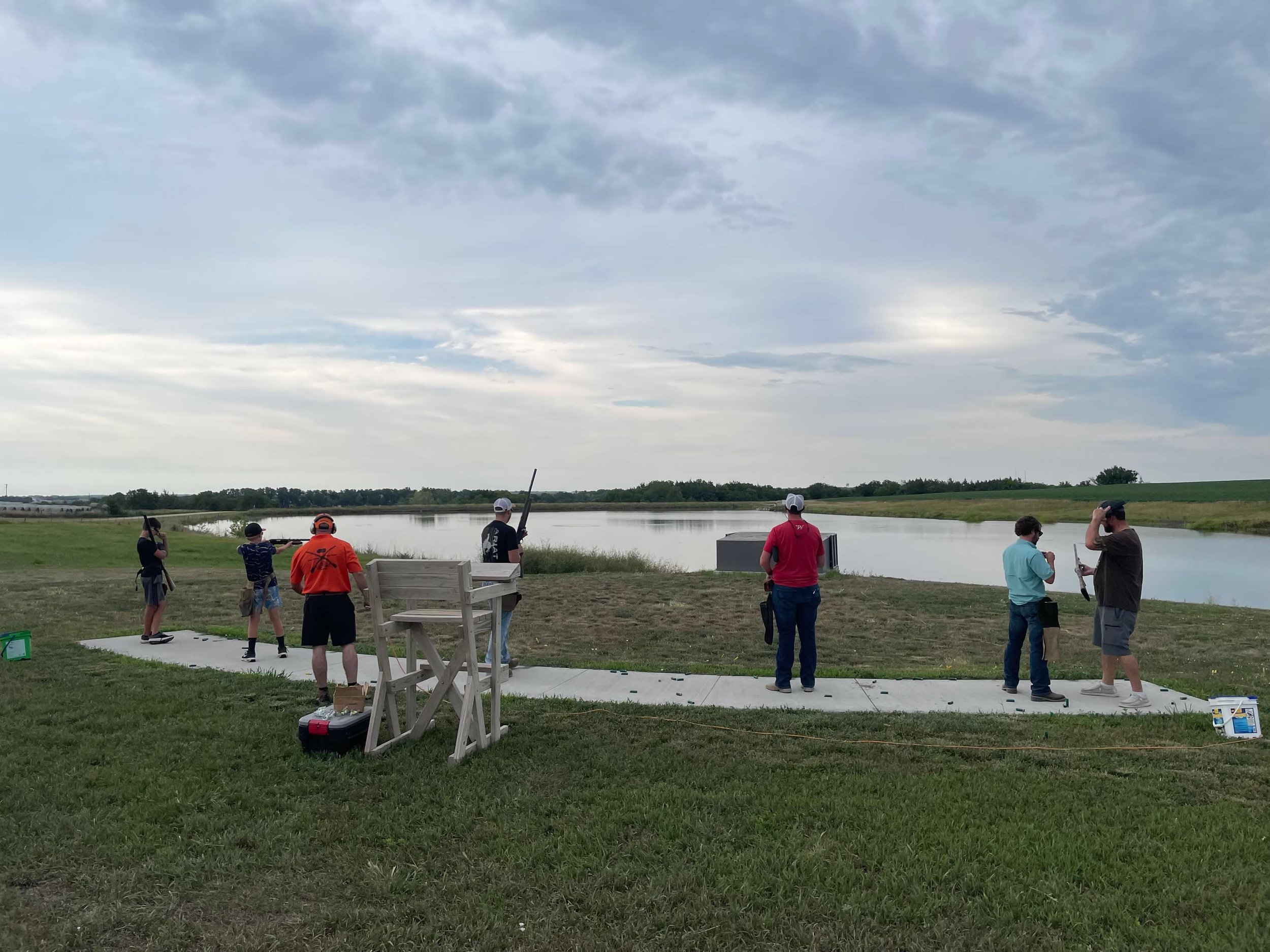 Trap Shooters with pond in background at Clay Center, KS in summer.