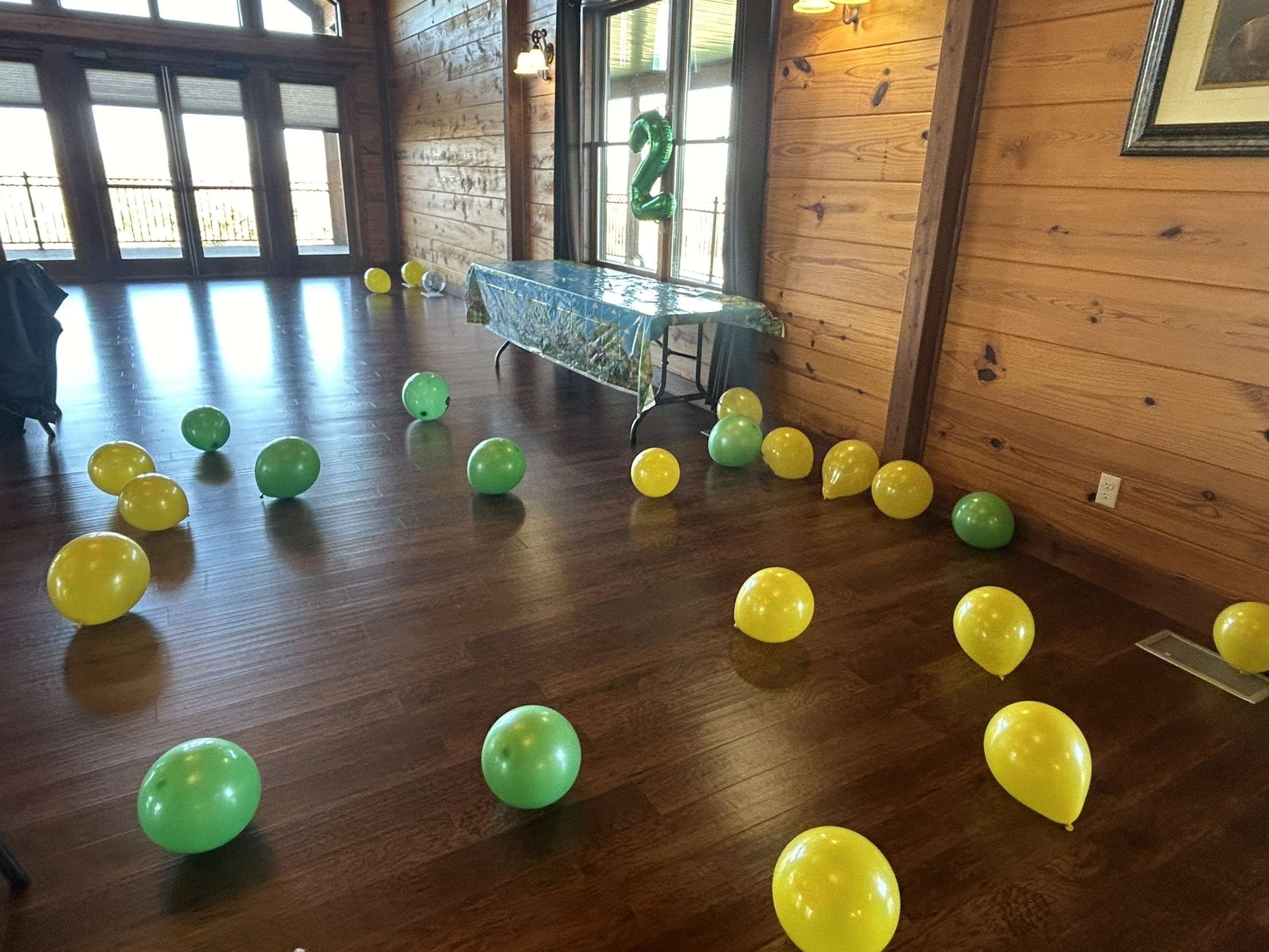 Green and yellow balloons on wood floor for 2 year old John Deere birthday party at Life's Finer Moments.