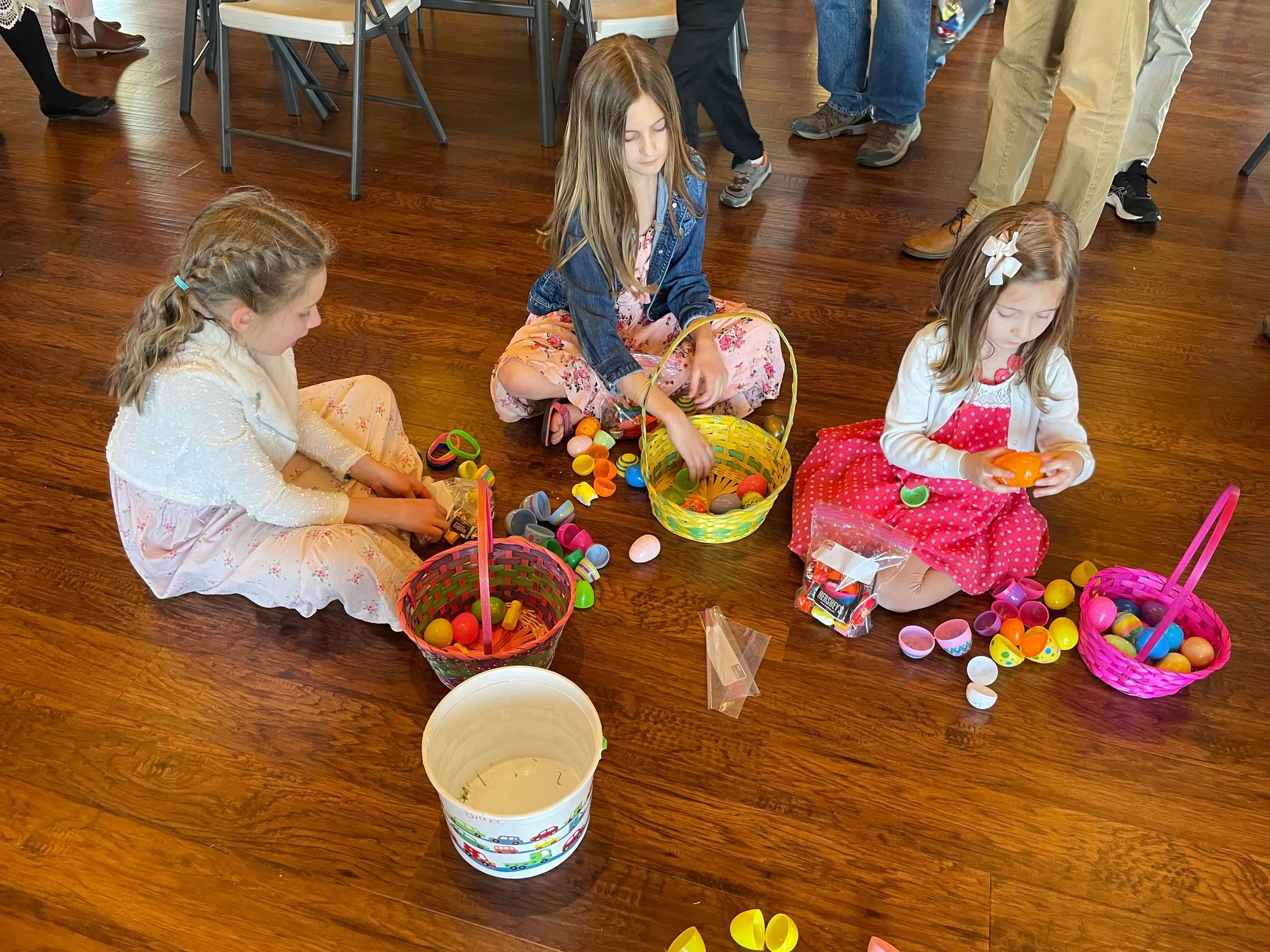 Young girls opening Easter Eggs from baskets on Great Room floor of Life's Finer Moments.