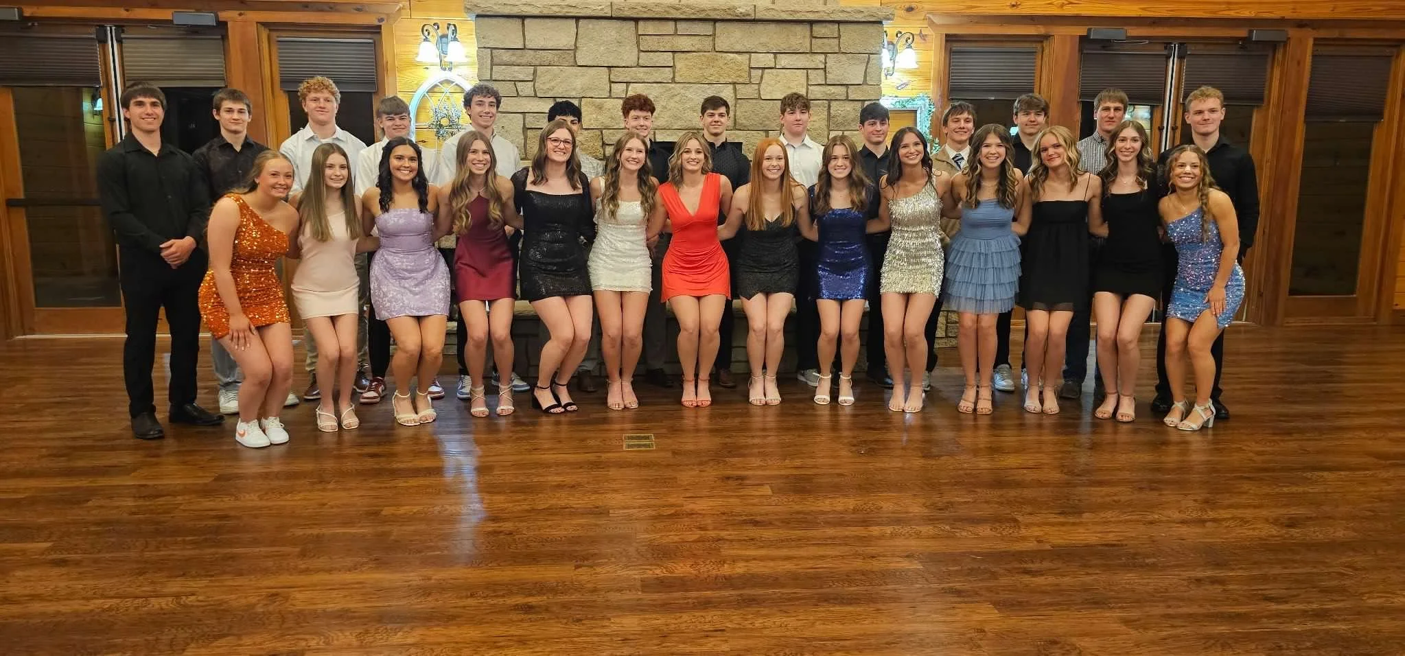 Prom dates posing in front of giant fireplace in large room