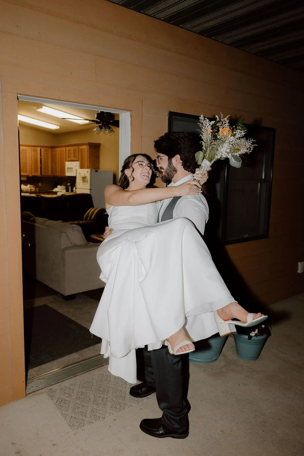 Grrom carrying bride over cabin threshold into cabin
