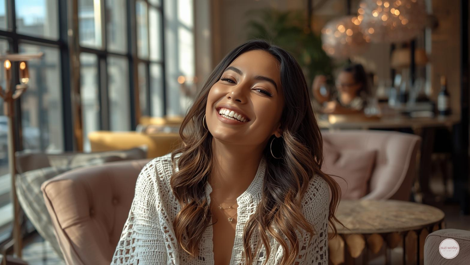 Smiling woman sitting in an upscale lobby, rose gold accents.