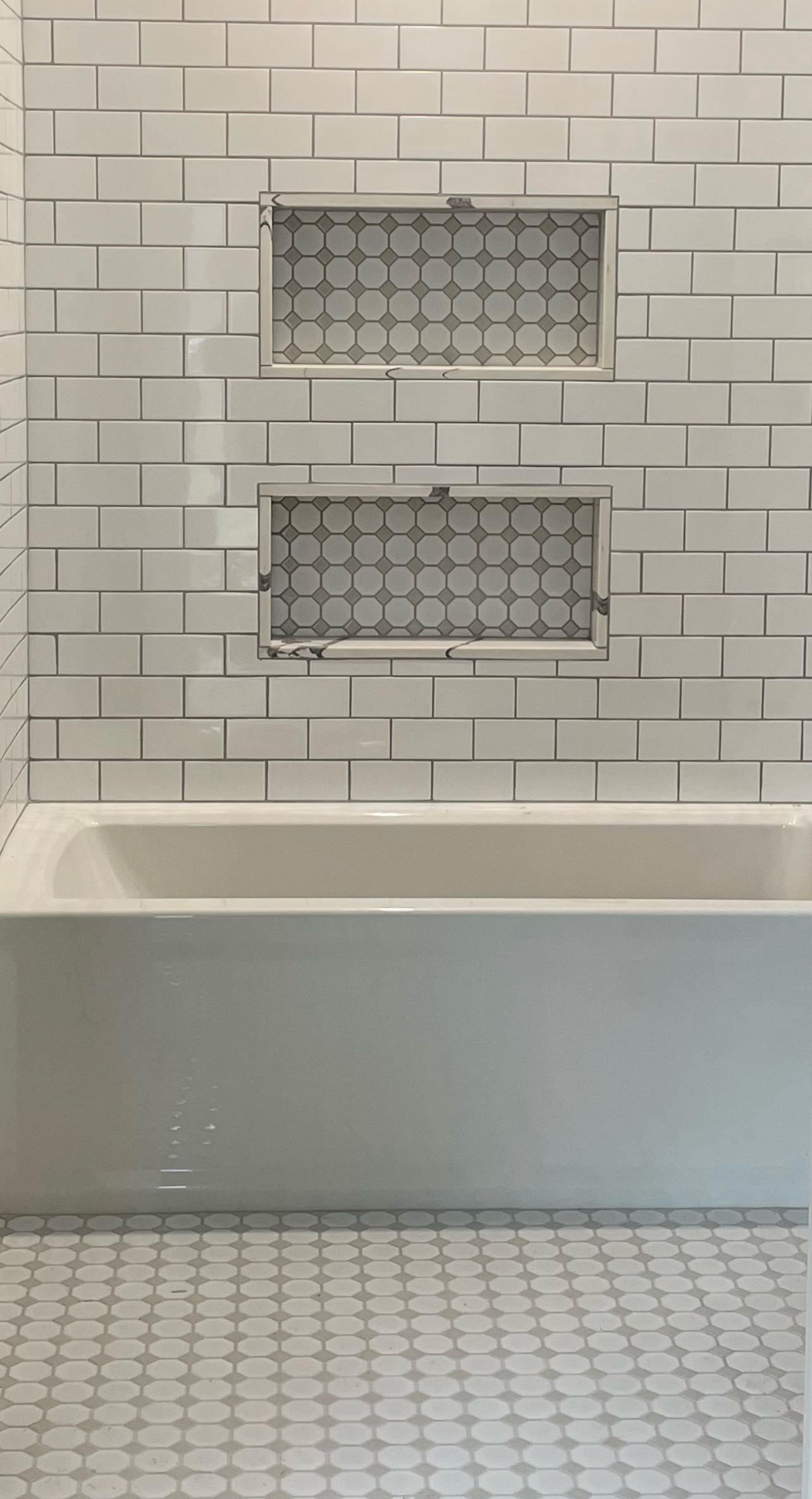 Incredible tile work for the floor and tub area with built in shelves that also feature incredible tiling. 