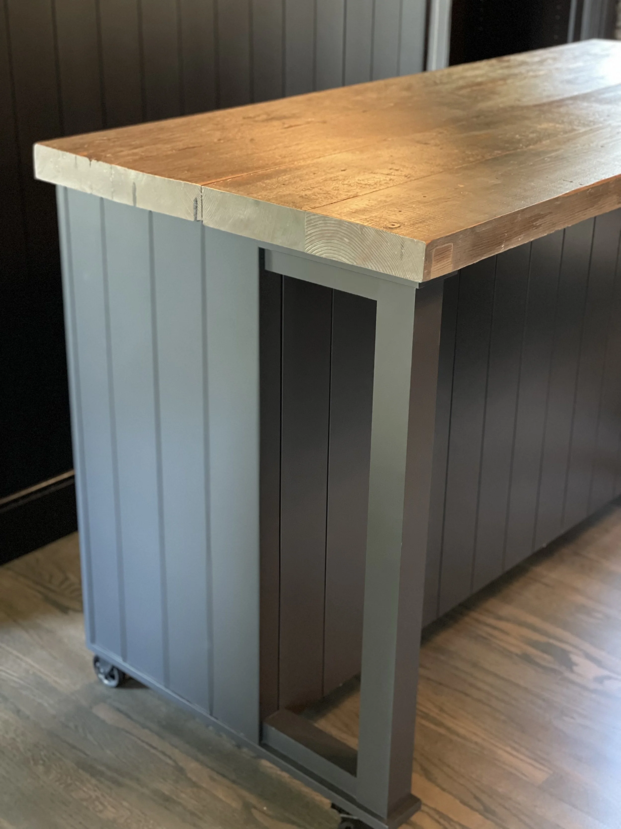 A custom built rolling counter top. Green base with a wooden top. Room to sit under as well.