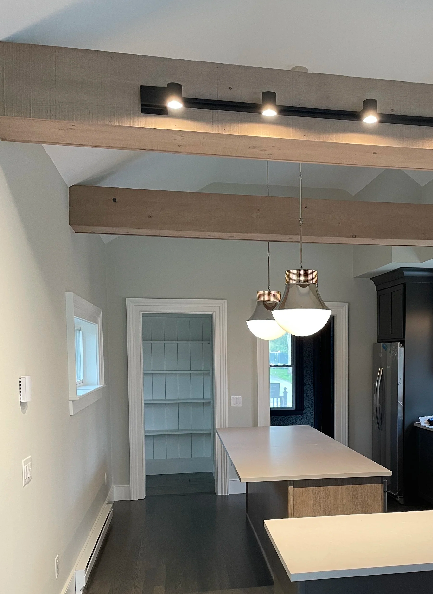 A newly remodeled kitchen with open shelving in the pantry, decorative polished nickel pendant lighting hang over the kitchen island.