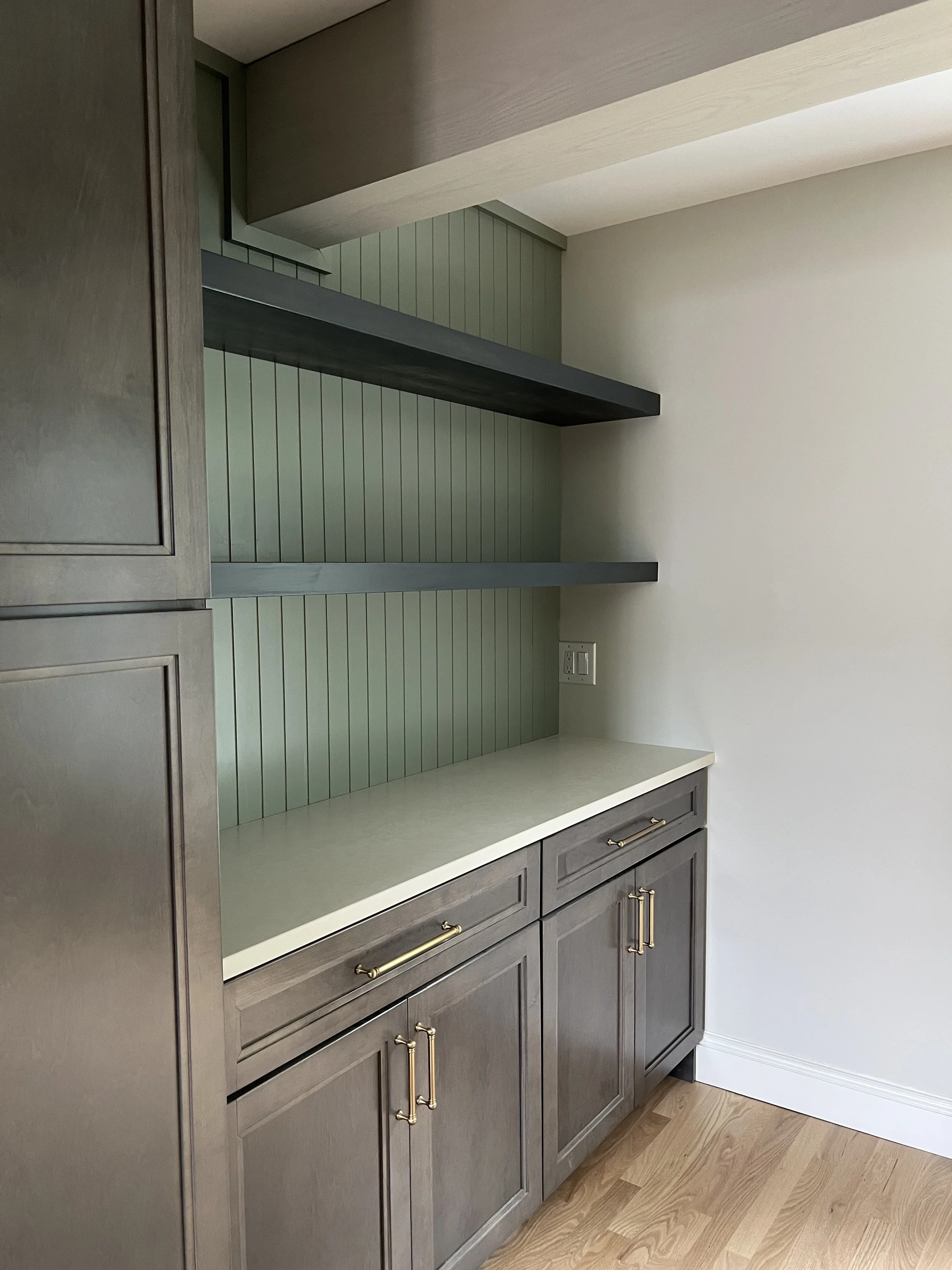 This drink station with maple stained cabinets, quartz counters, custom open shelving and beadboard wall detail were part of a newly renovated kitchen in Hamilton, NY. Completed by a construction company from Hamilton.
