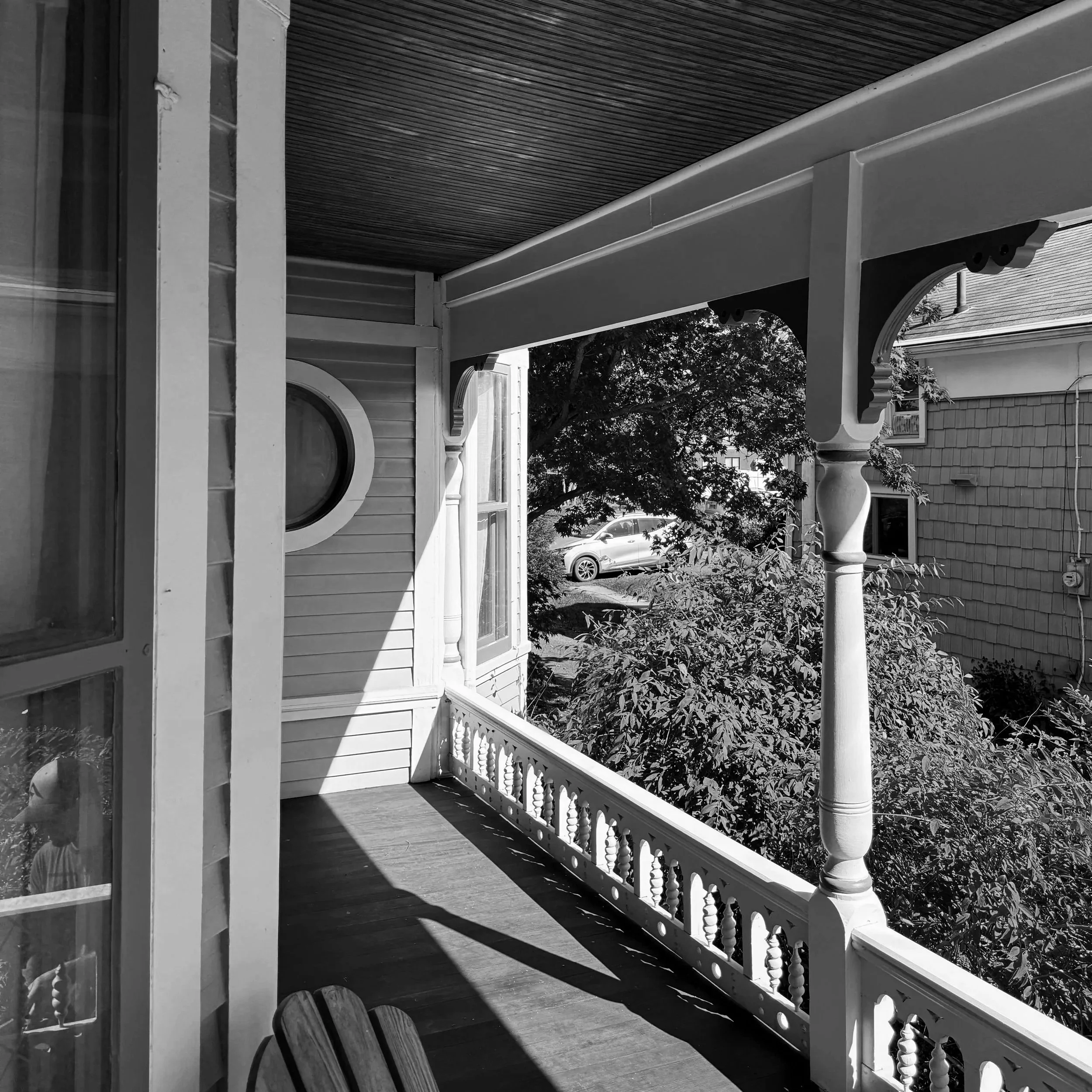 Restored front porch with cedar decking, recreated custom millwork, and an original round window in Central New York.
